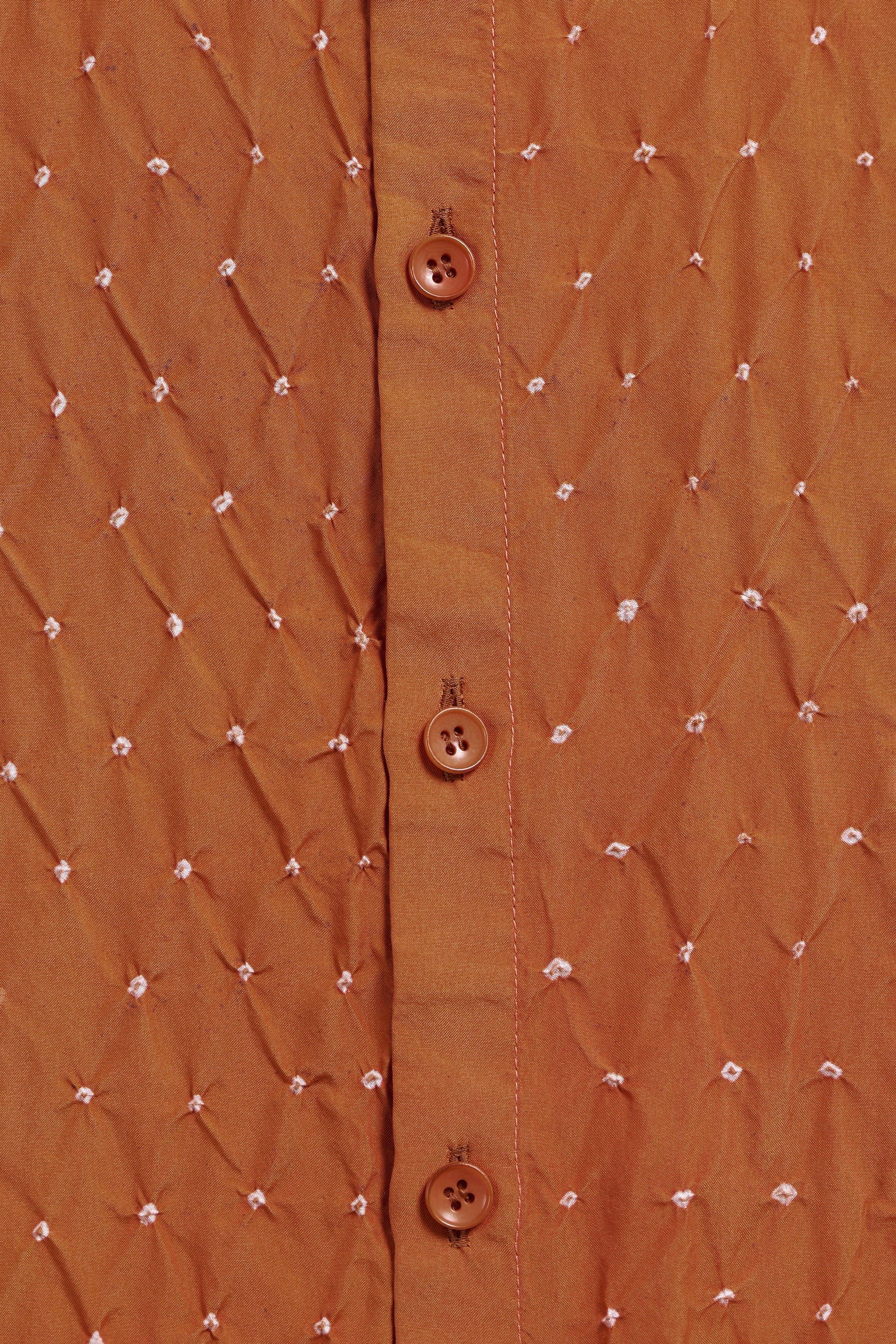 Close-up of a brown textured shirt with button