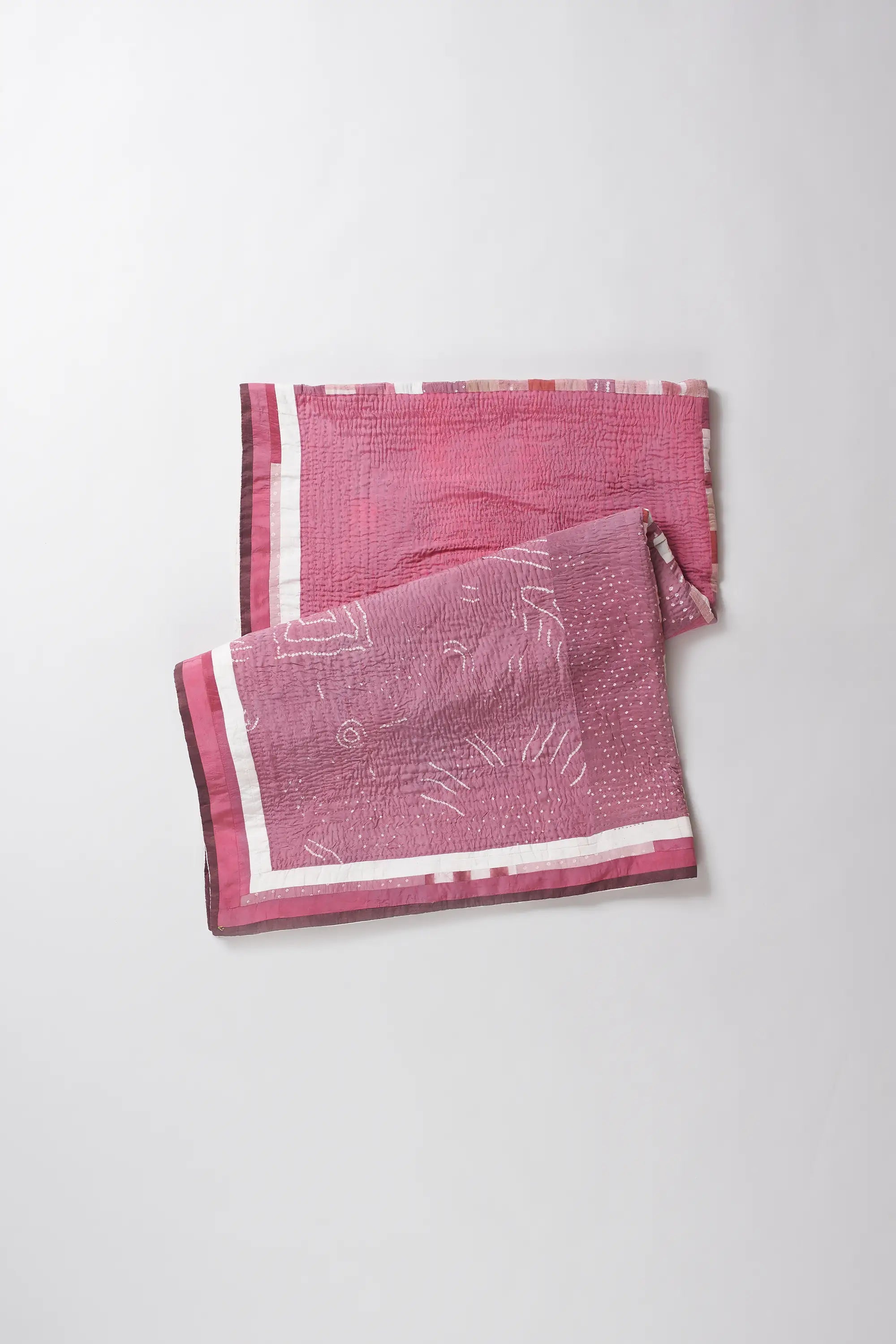 Pink patterned quilt on a white background
