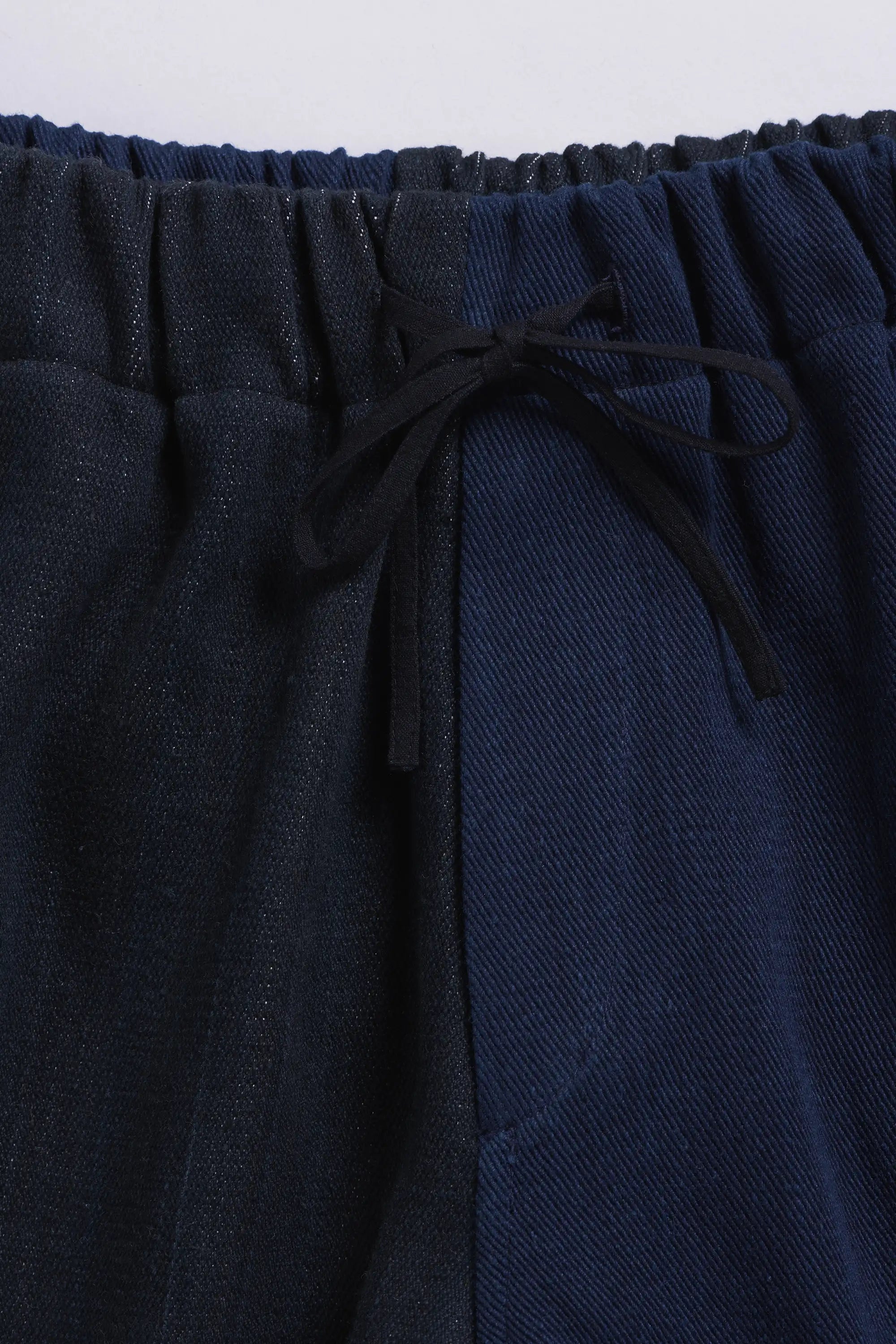 Indigo pants with a drawstring waist on a light grey background
