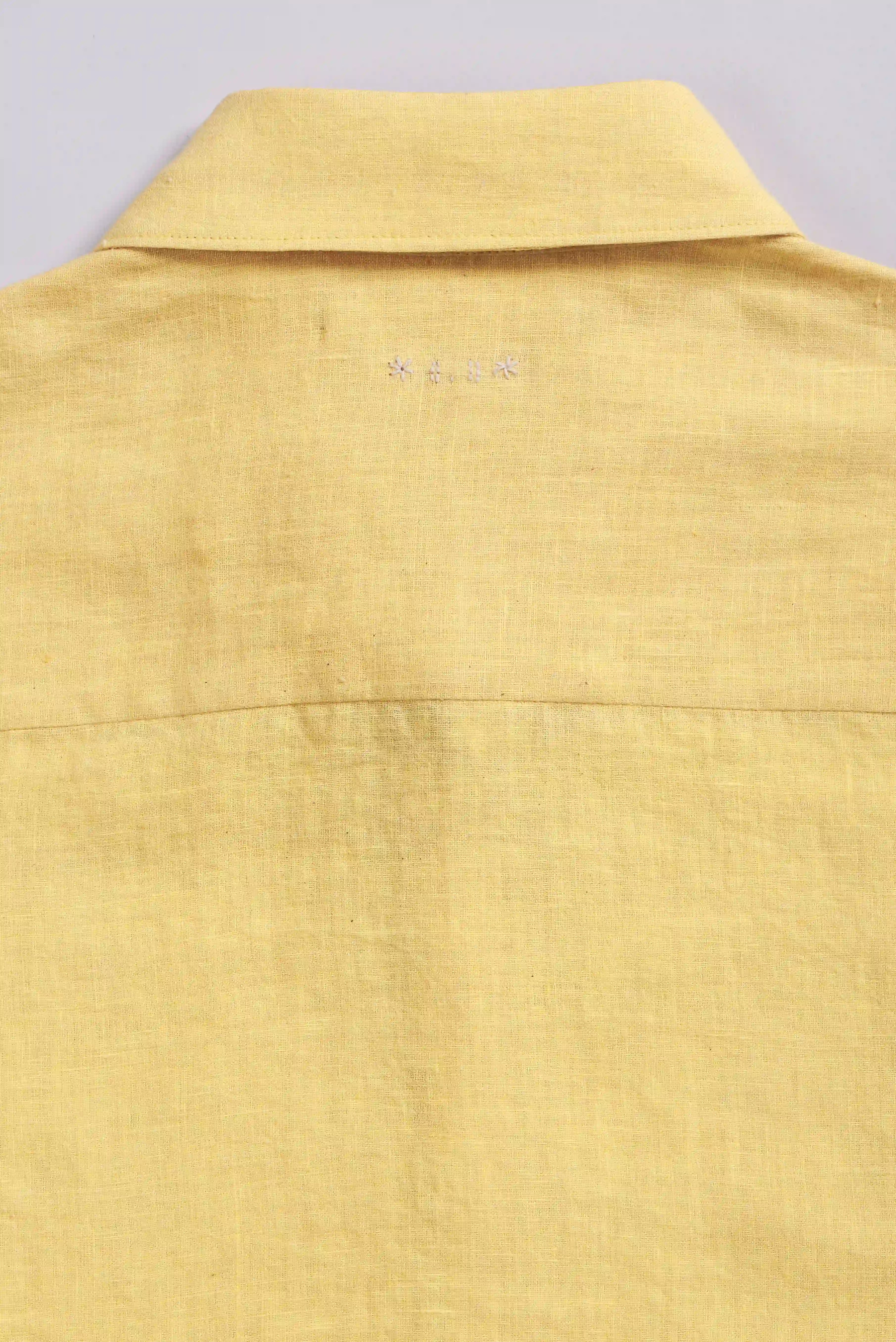 Yellow shirt collar with a brand logo on a light grey background