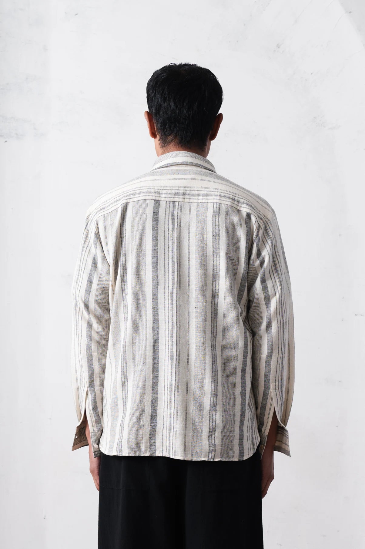 back shot of a person wearing a striped shirt on a light grey background