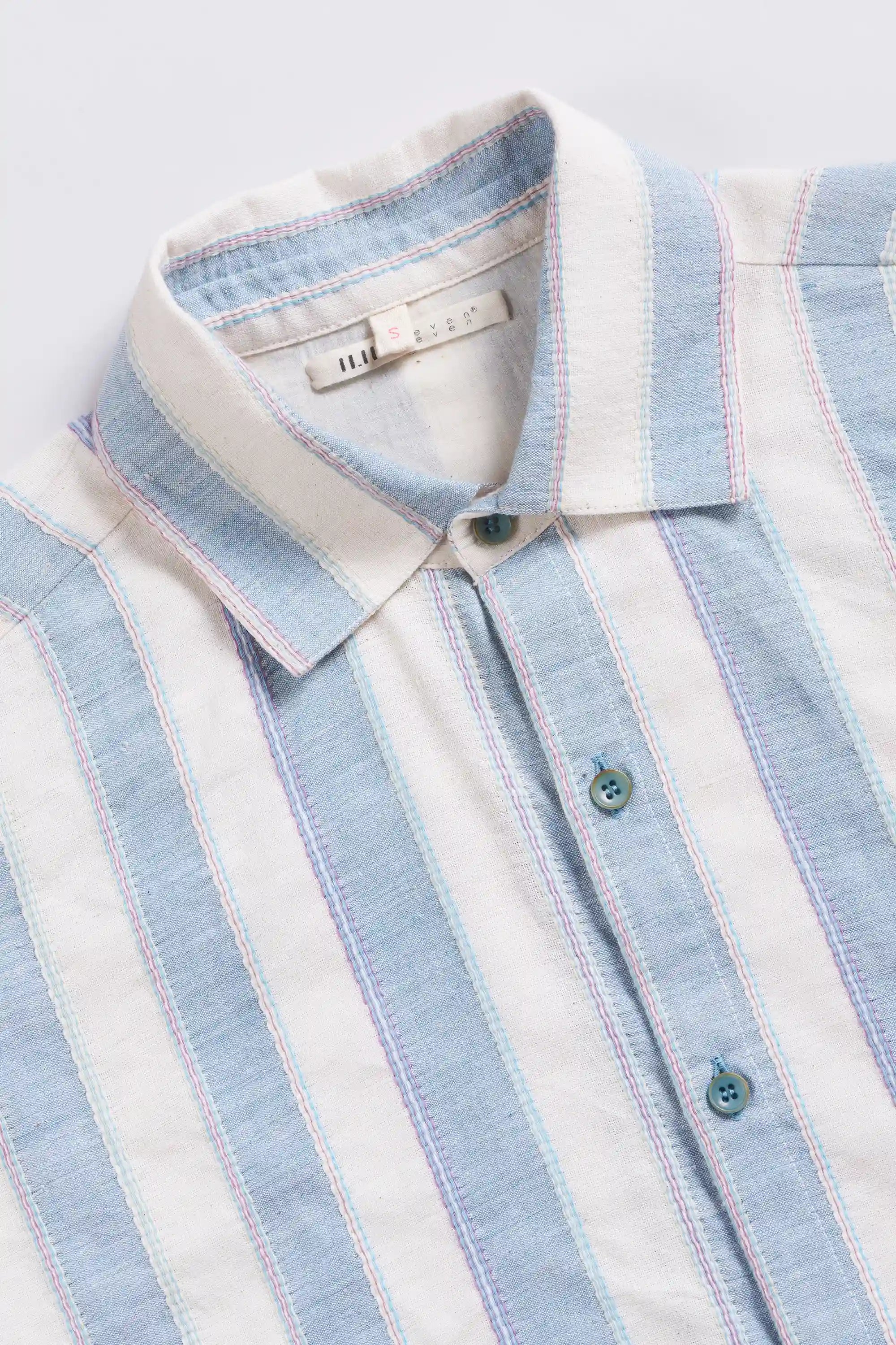 Close-up of a light blue and white striped shirt with a collar on a light grey background
