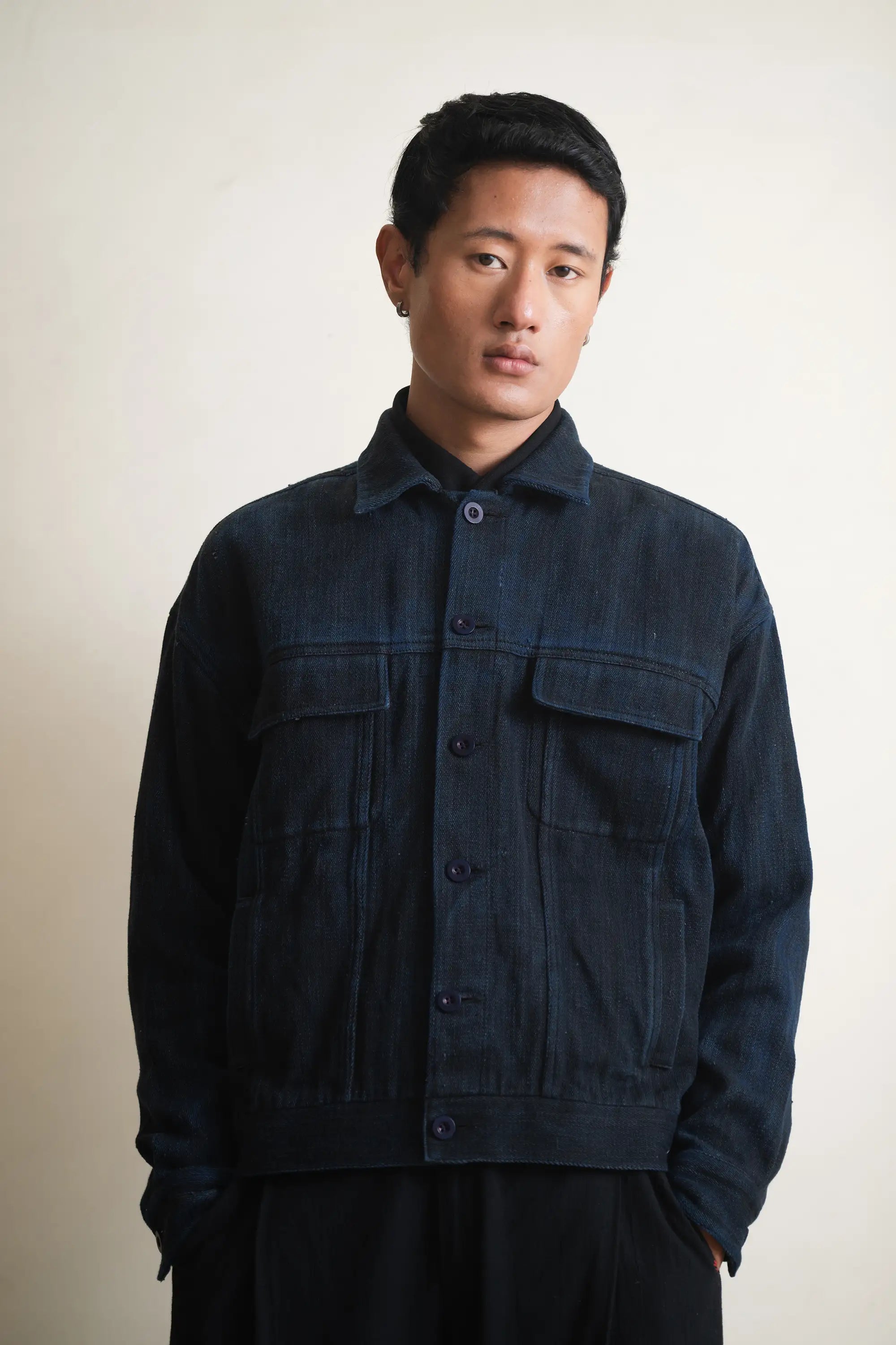 Man wearing a dark blue jacket against a light grey background