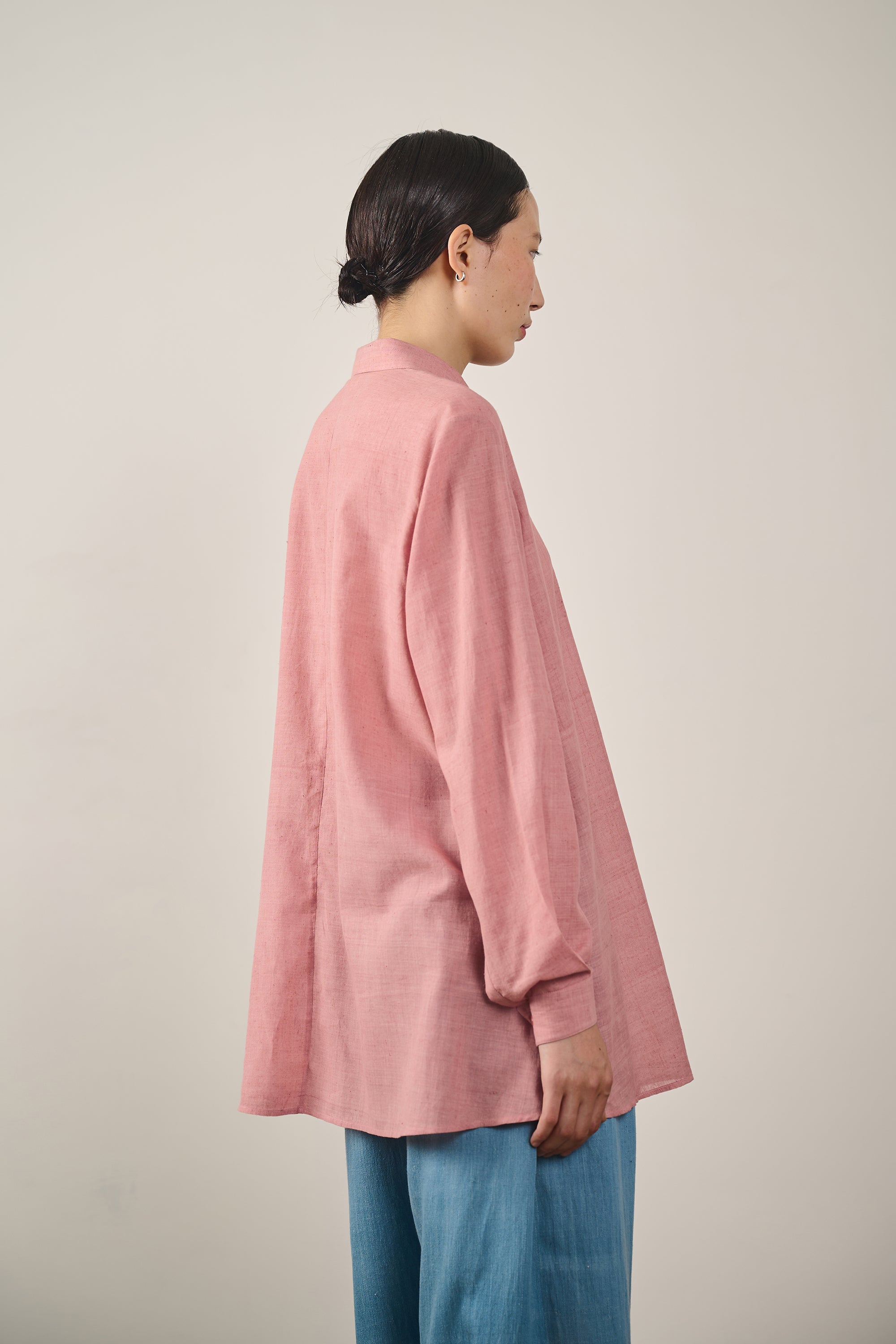 A side shot of a woman wearing chalk pink shirt