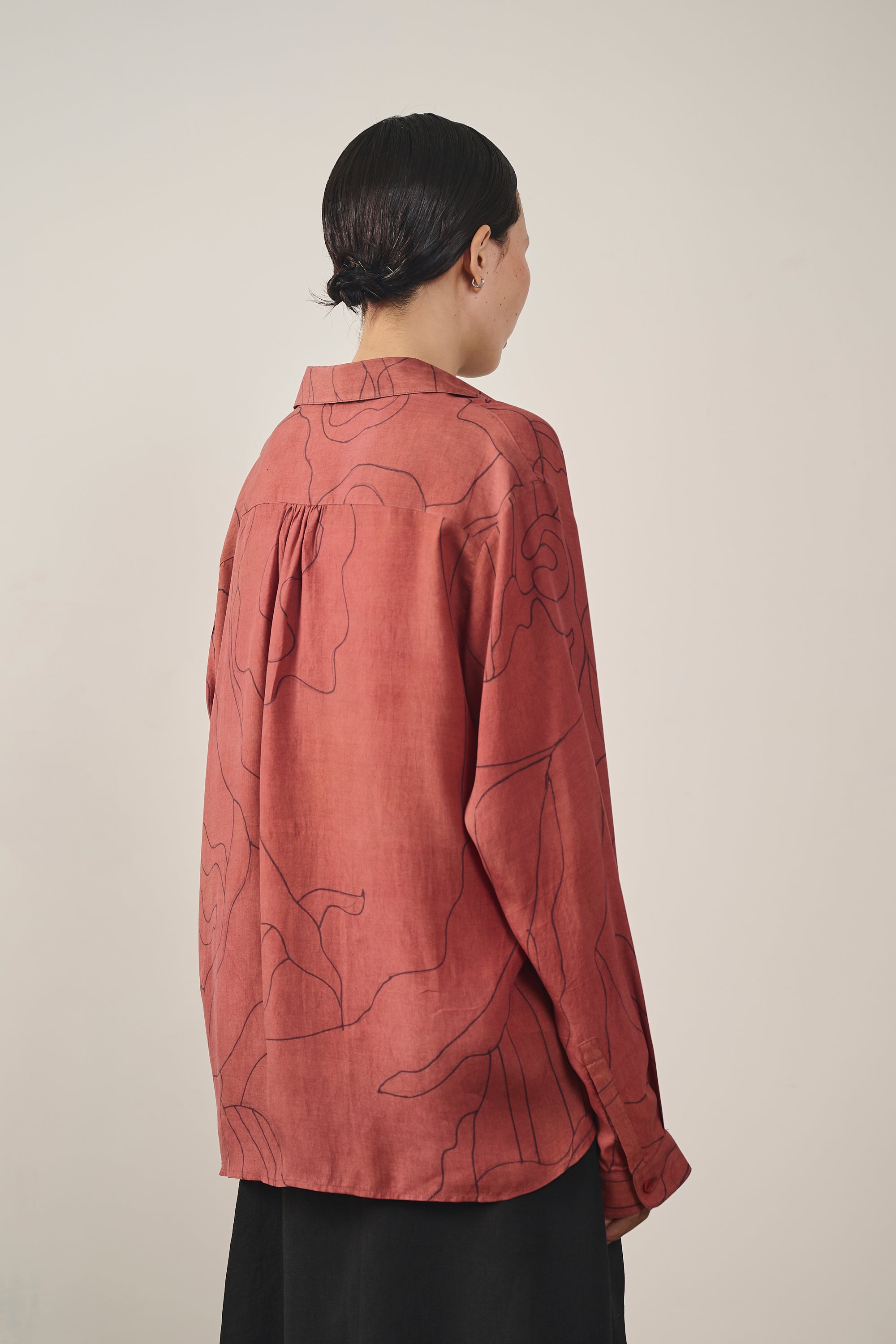 A back shot of a woman wearing rouge pink shirt