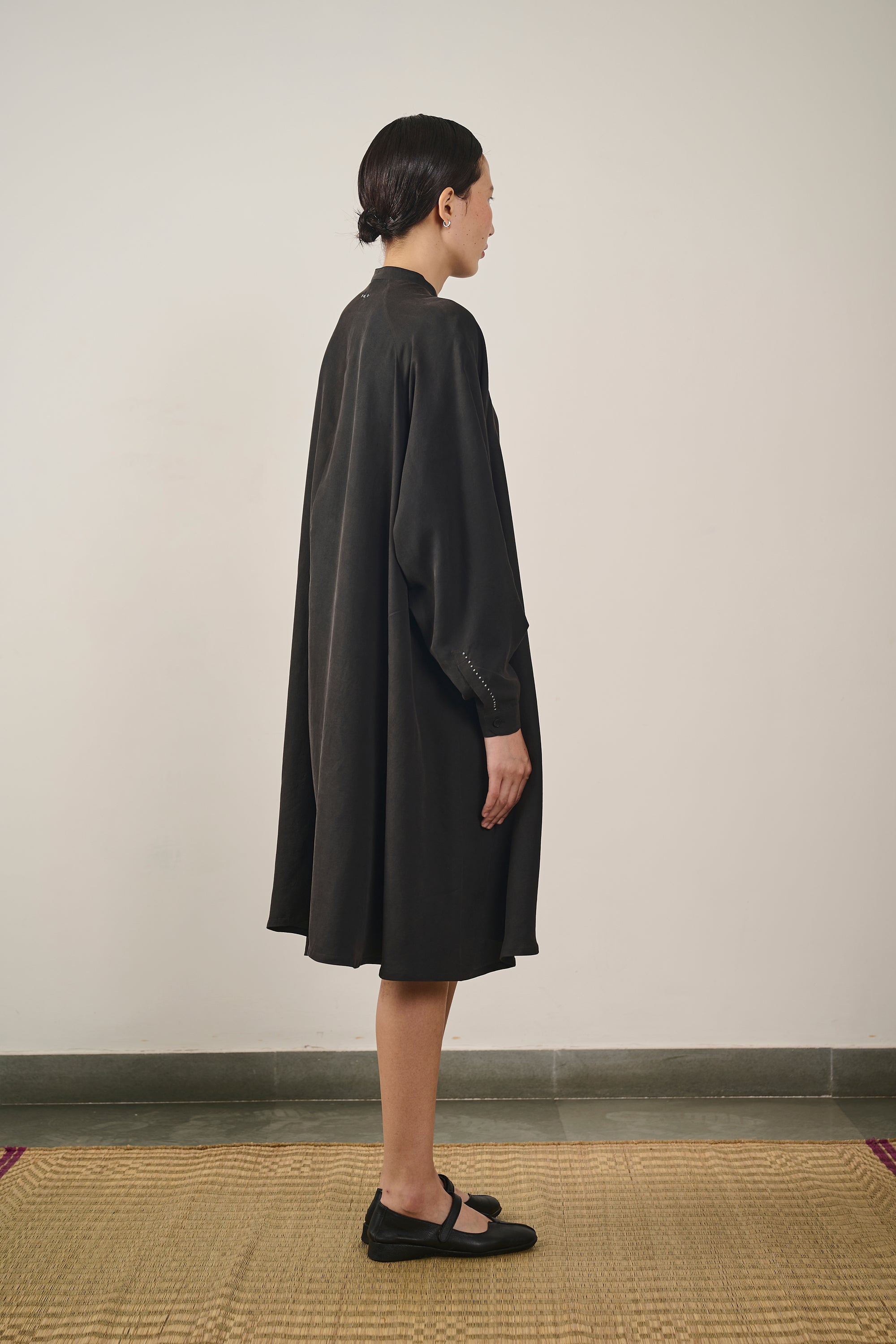A side shot of a woman wearing black silk dress