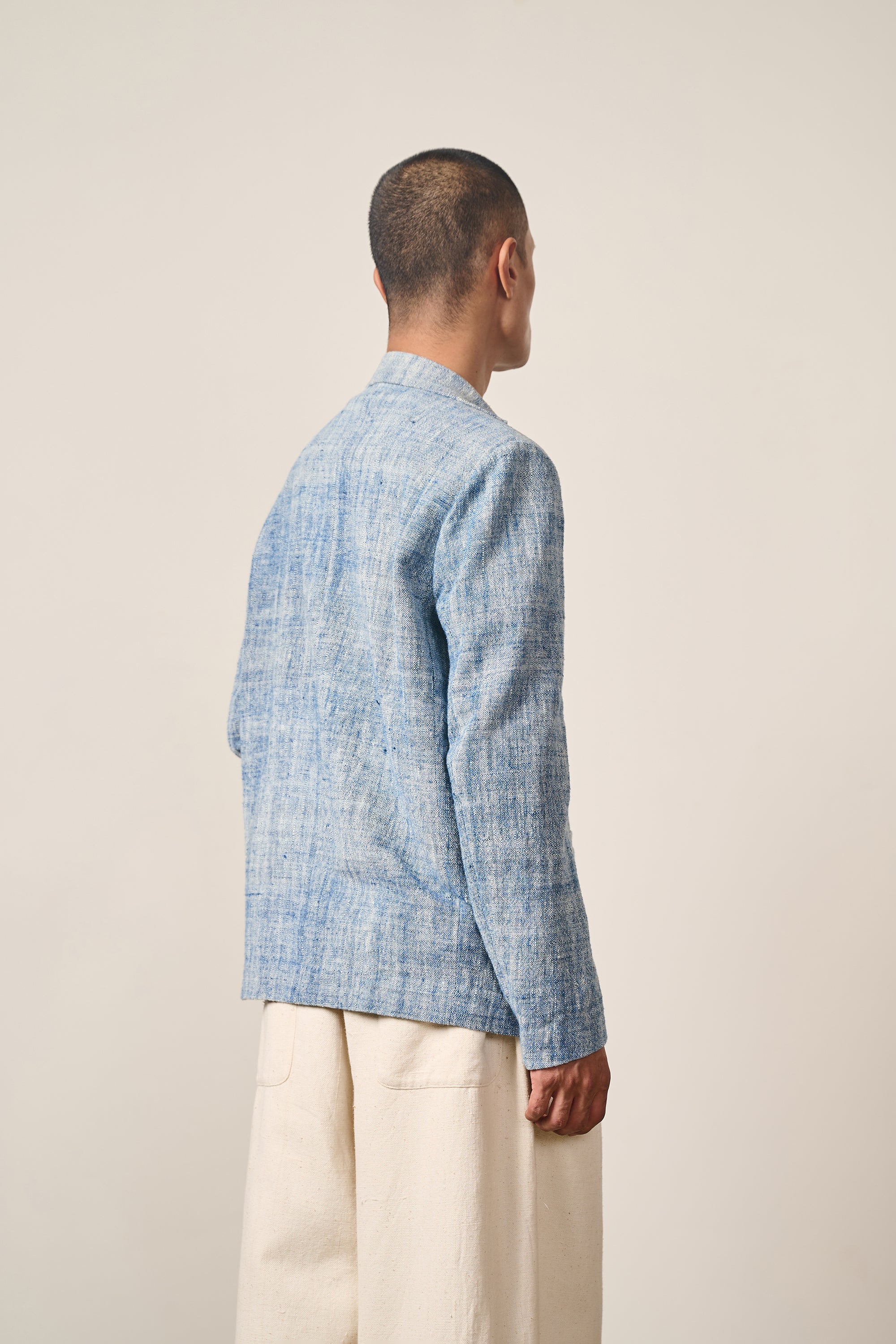 A back shot of a man wearing medium indigo jacket