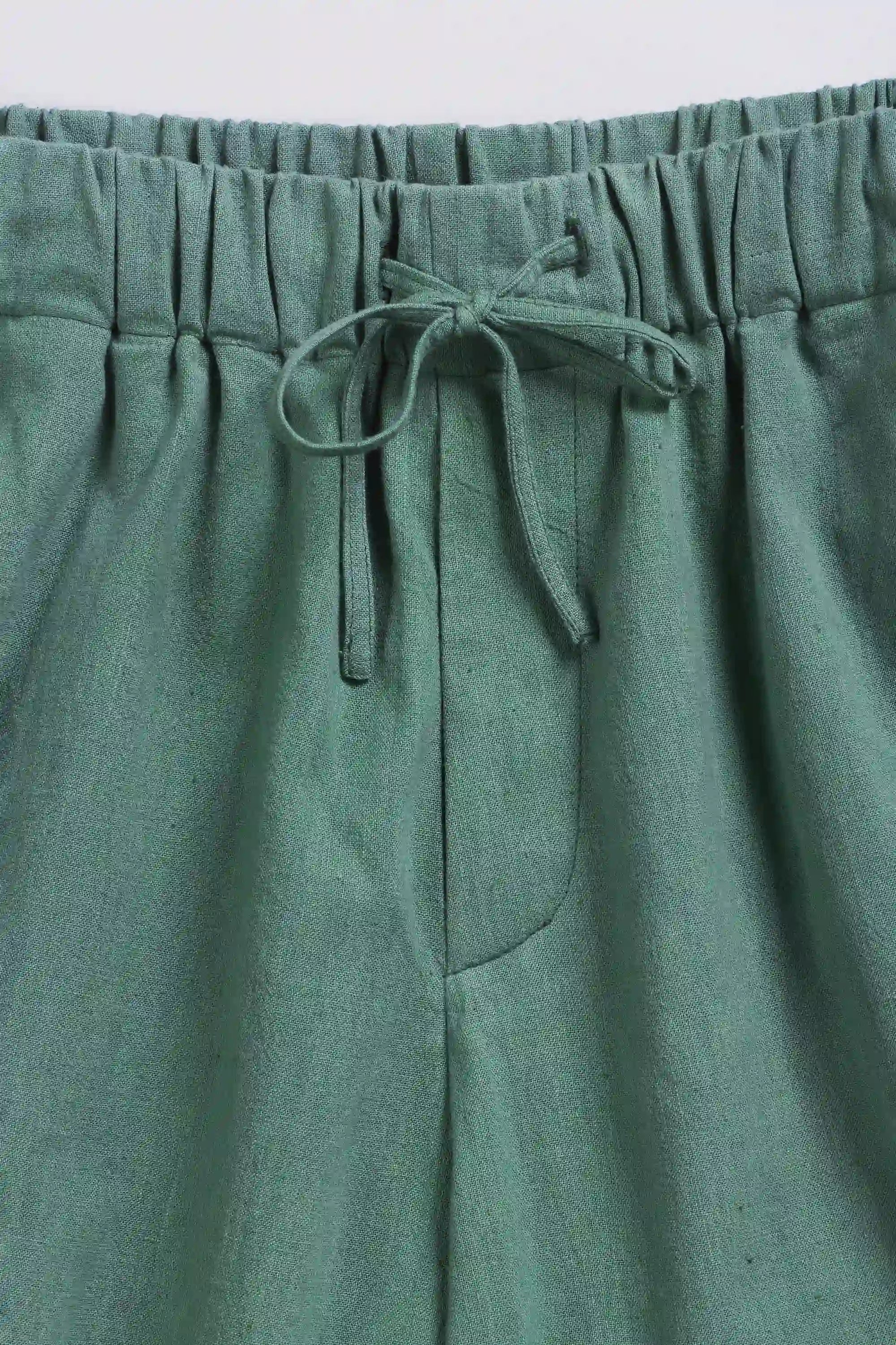 Green pants with an elastic waistband and drawstring on a light grey background