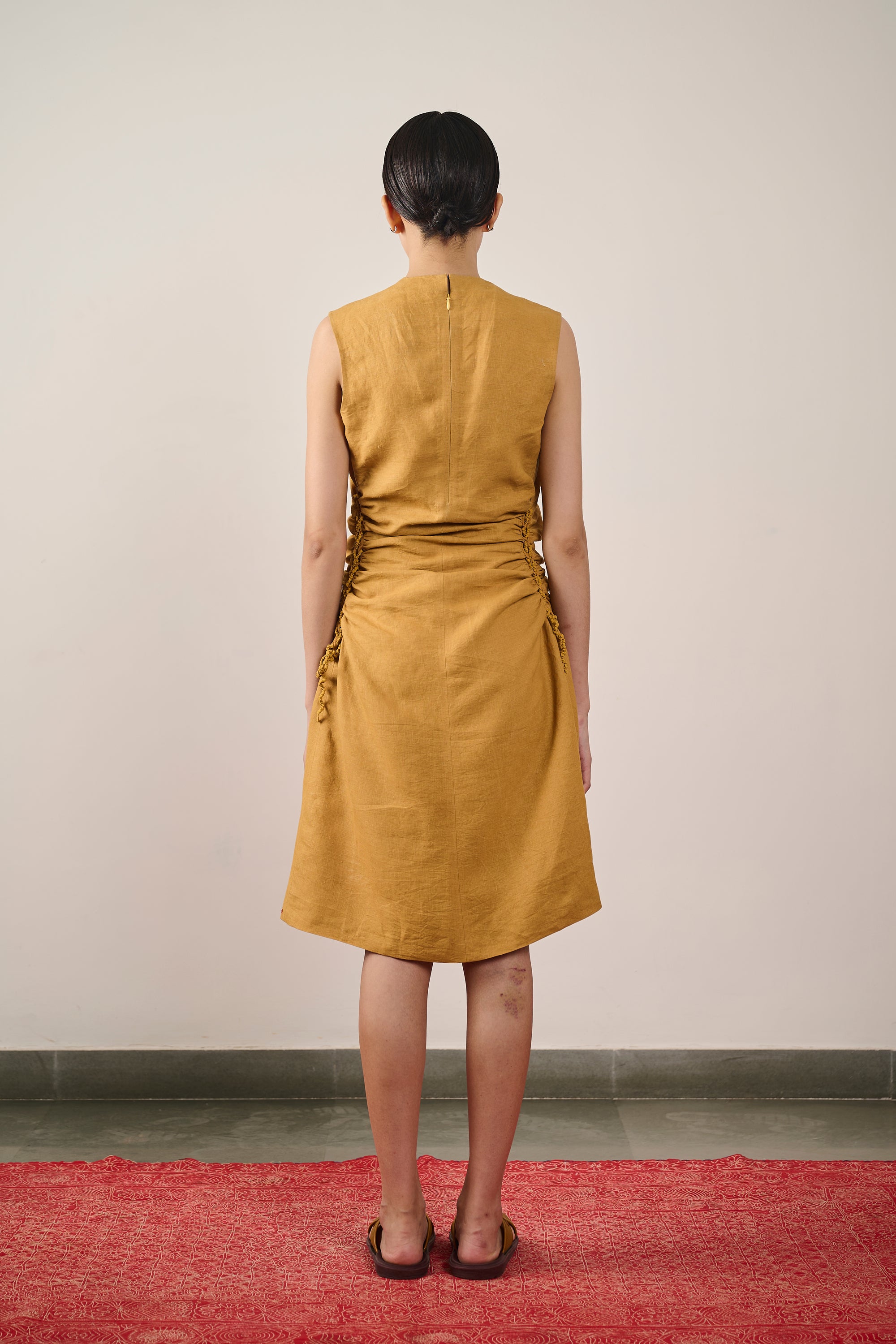 A back shot of a woman wearing mustard yellow dress