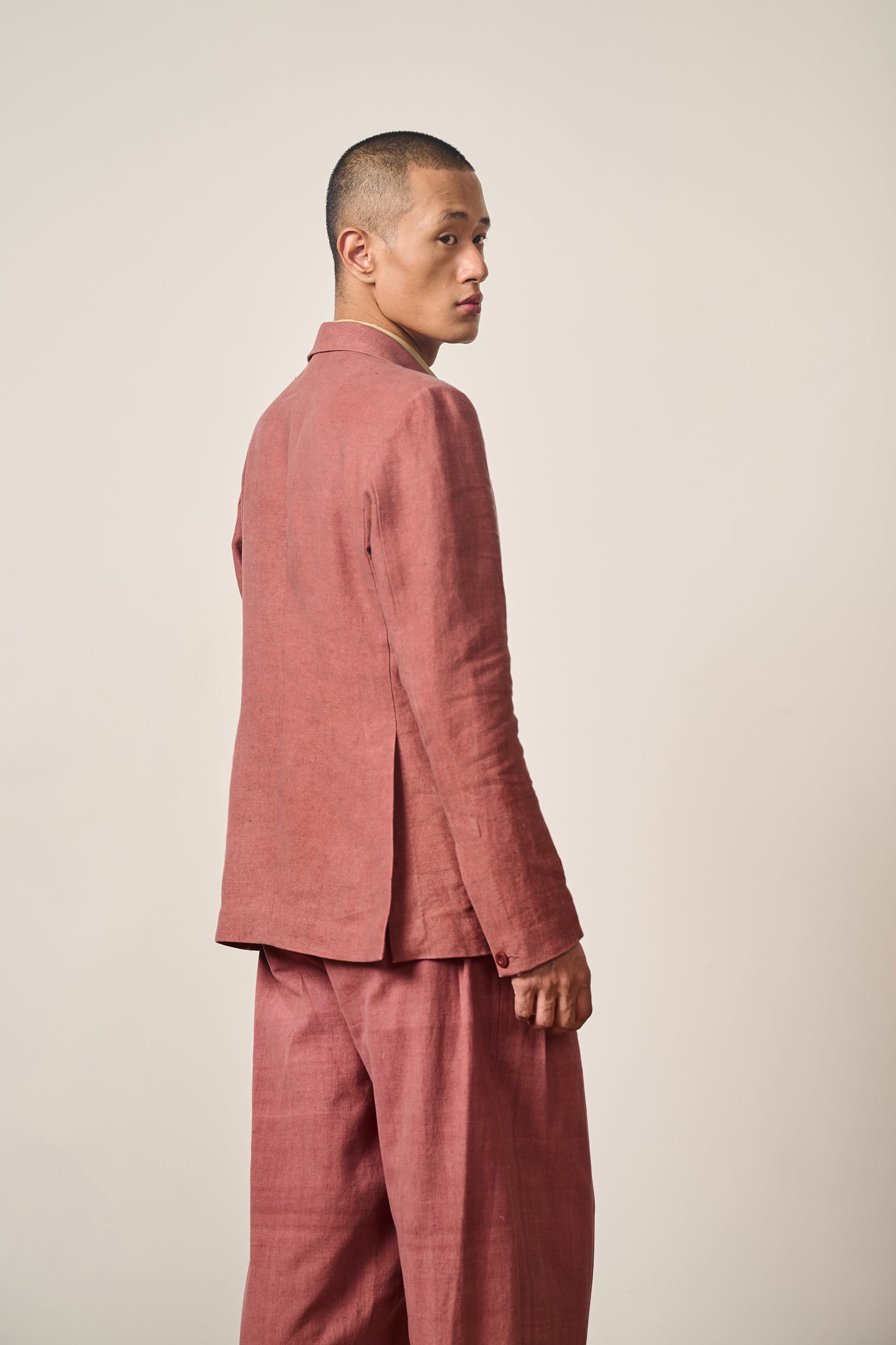 A side shot of a man wearing linen rouge pink jacket