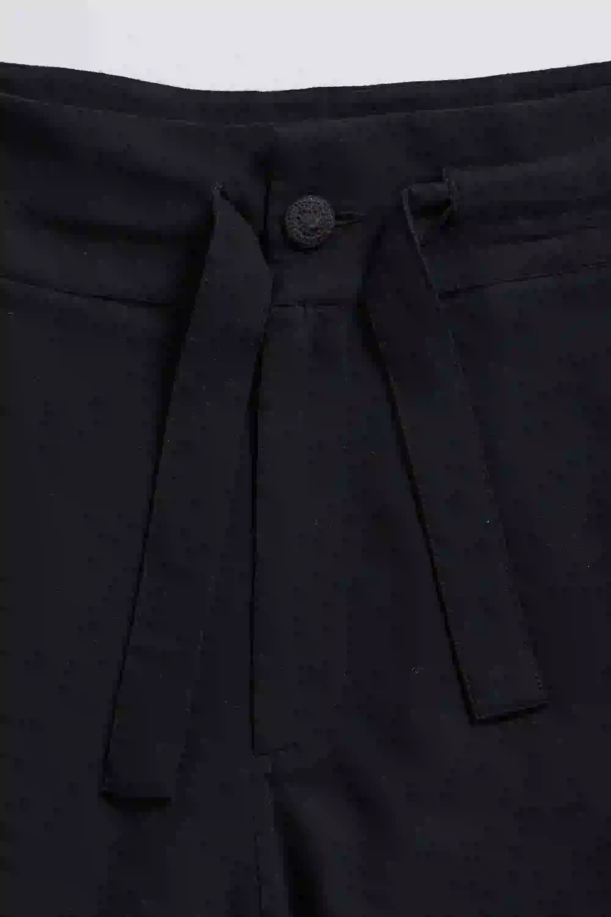 Close-up of black pants with a button on a white background