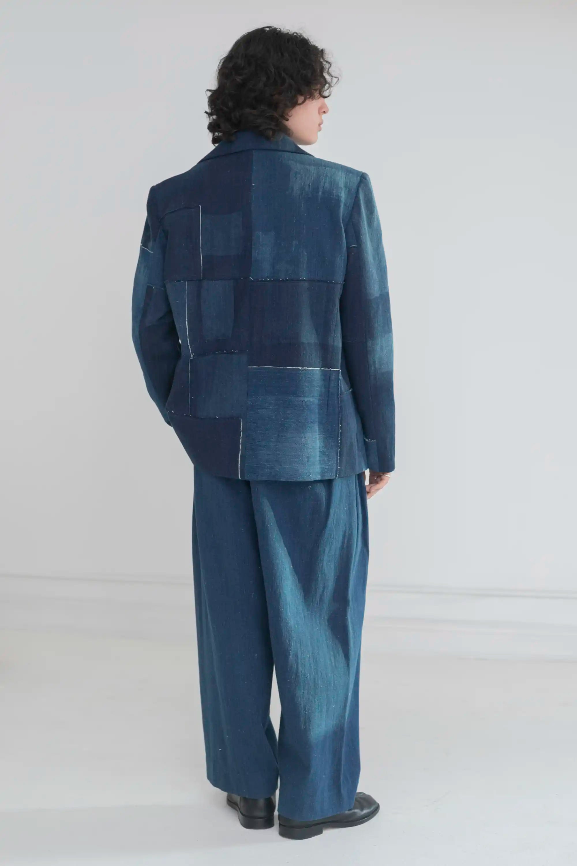 A back shot of a man wearing patchwork denim jacket