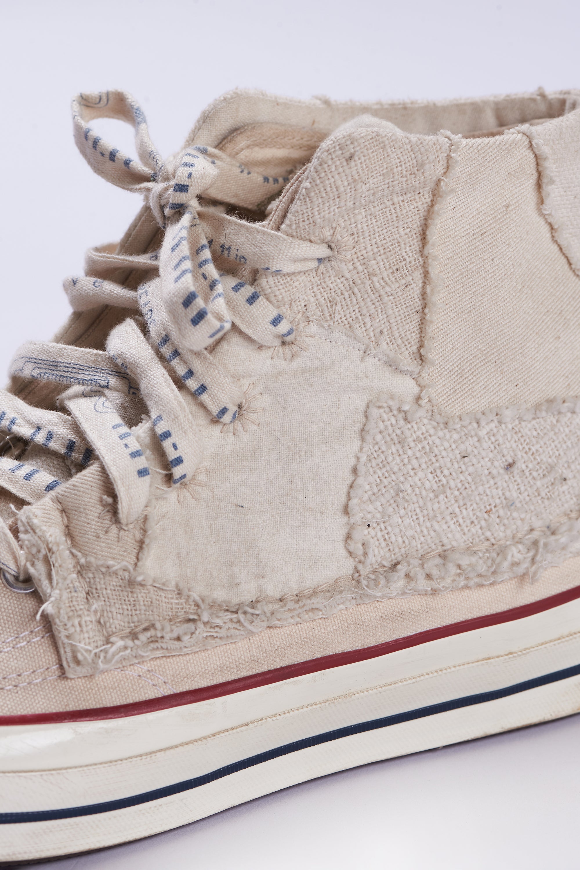 A close-up shot of ecru converse shoes with patchwork