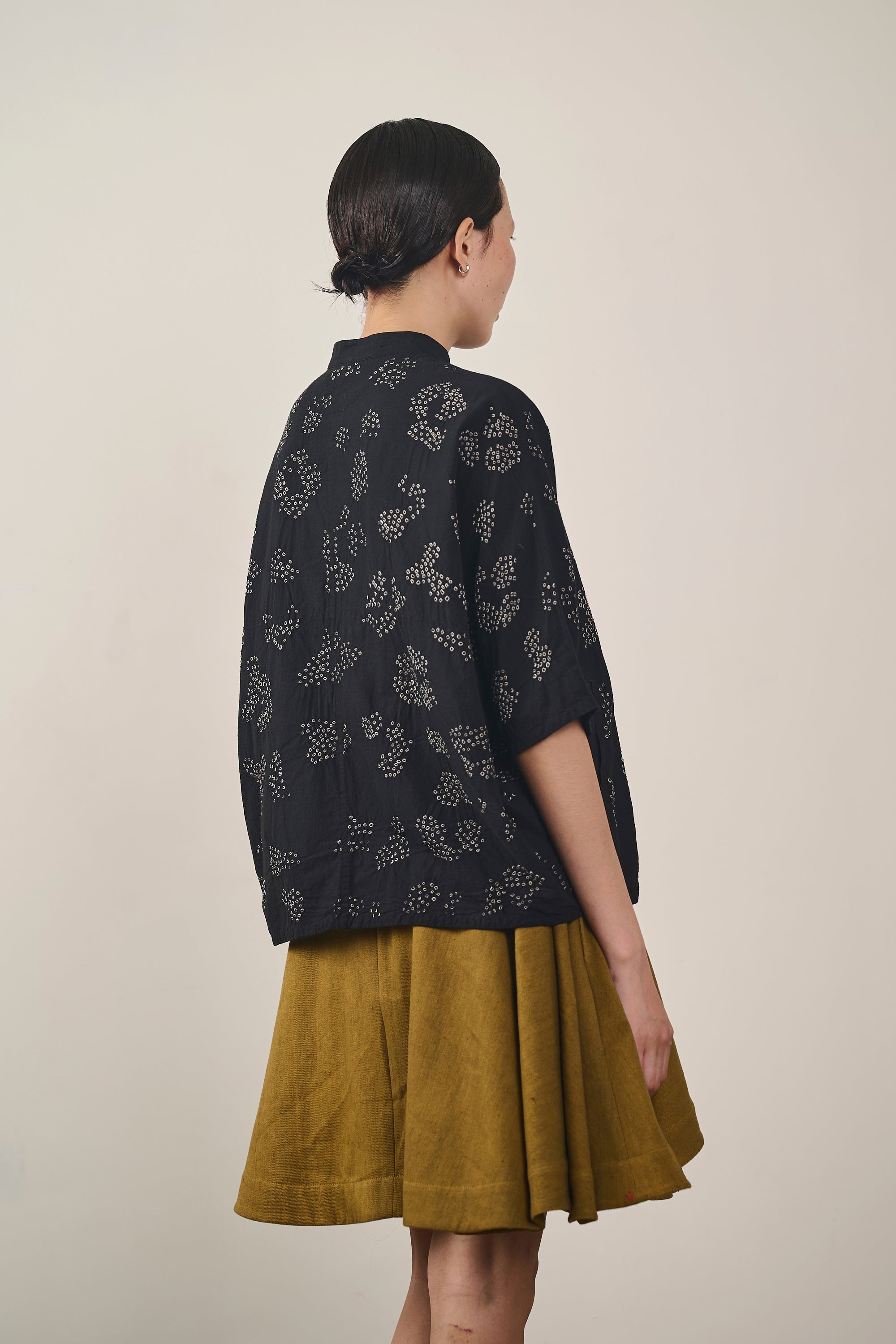 A back shot of a women a black bandhani shirt
