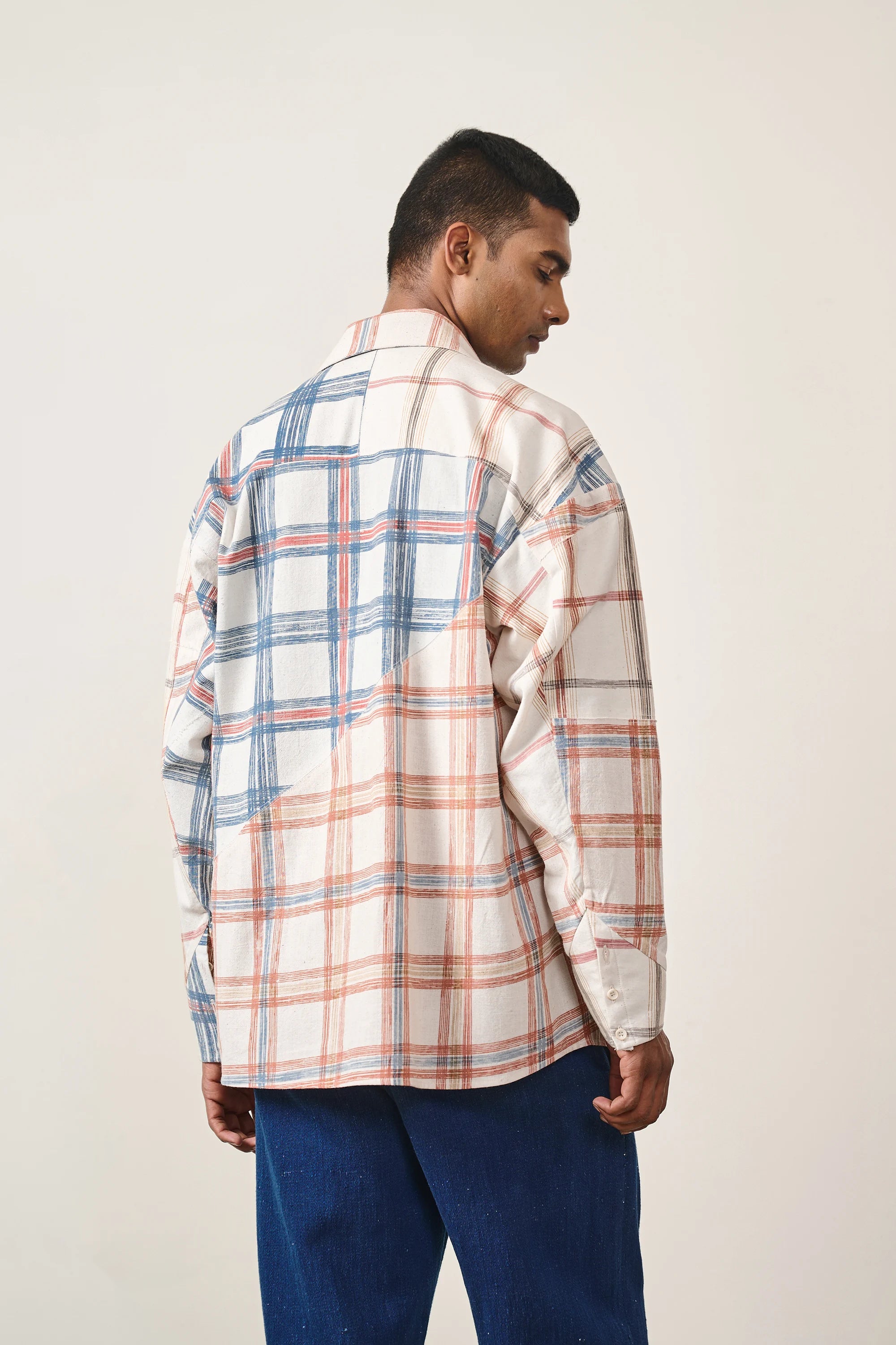 A back shot of a man wearing multi colour shirt