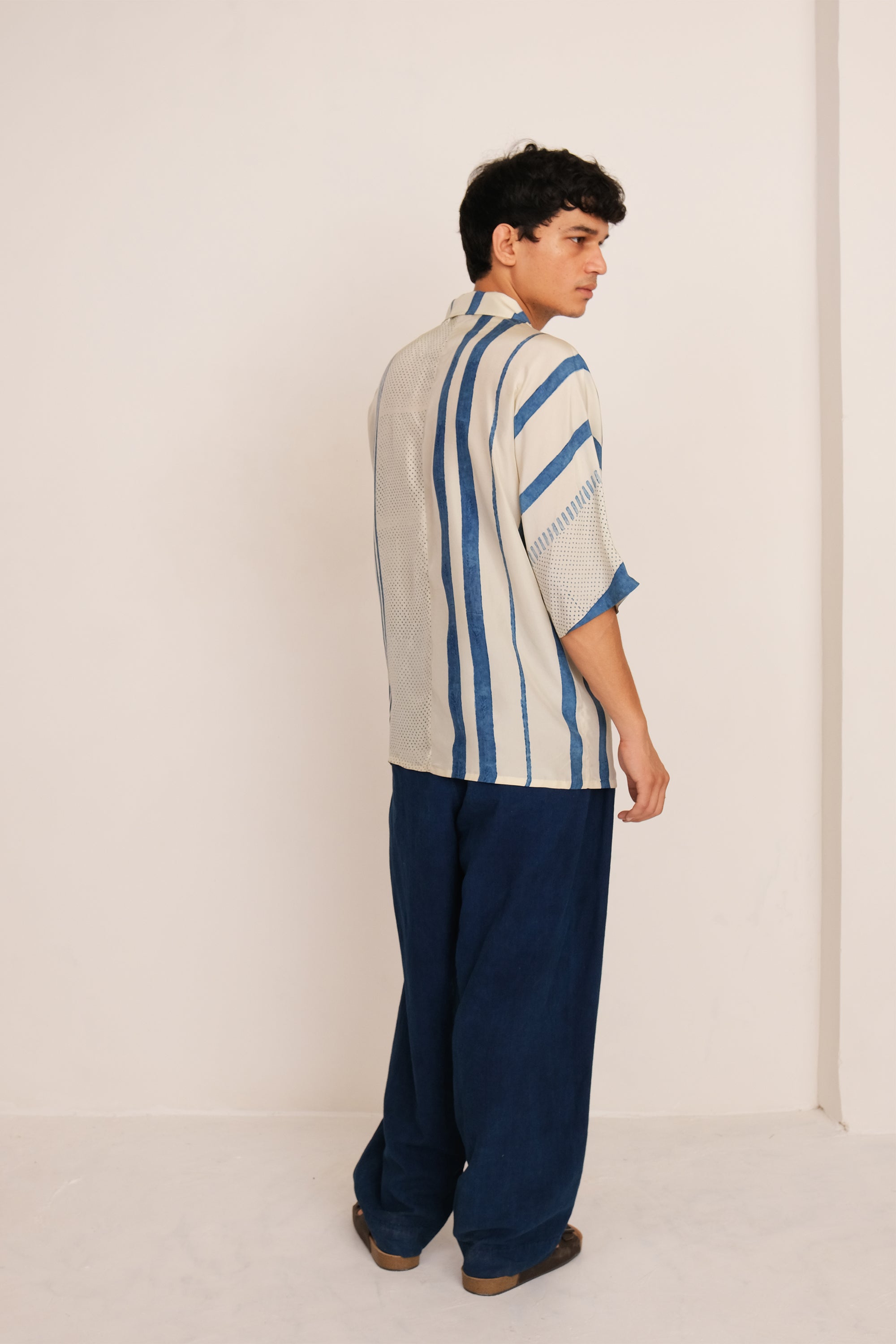 A side shot of a man wearing ecru shirt