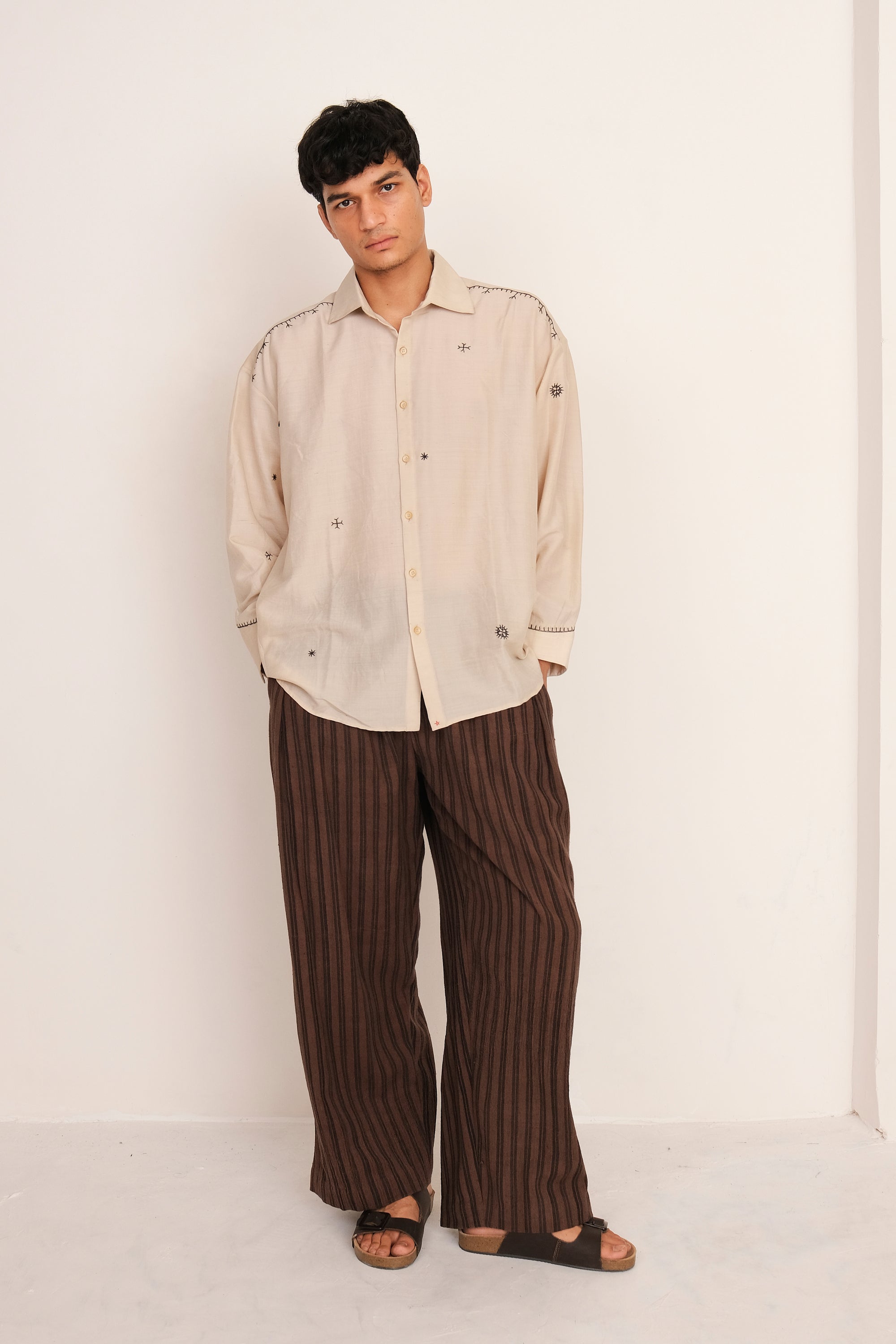 Front shot of man wearing a Ecru shirt and burnt umber striped pants against a white background