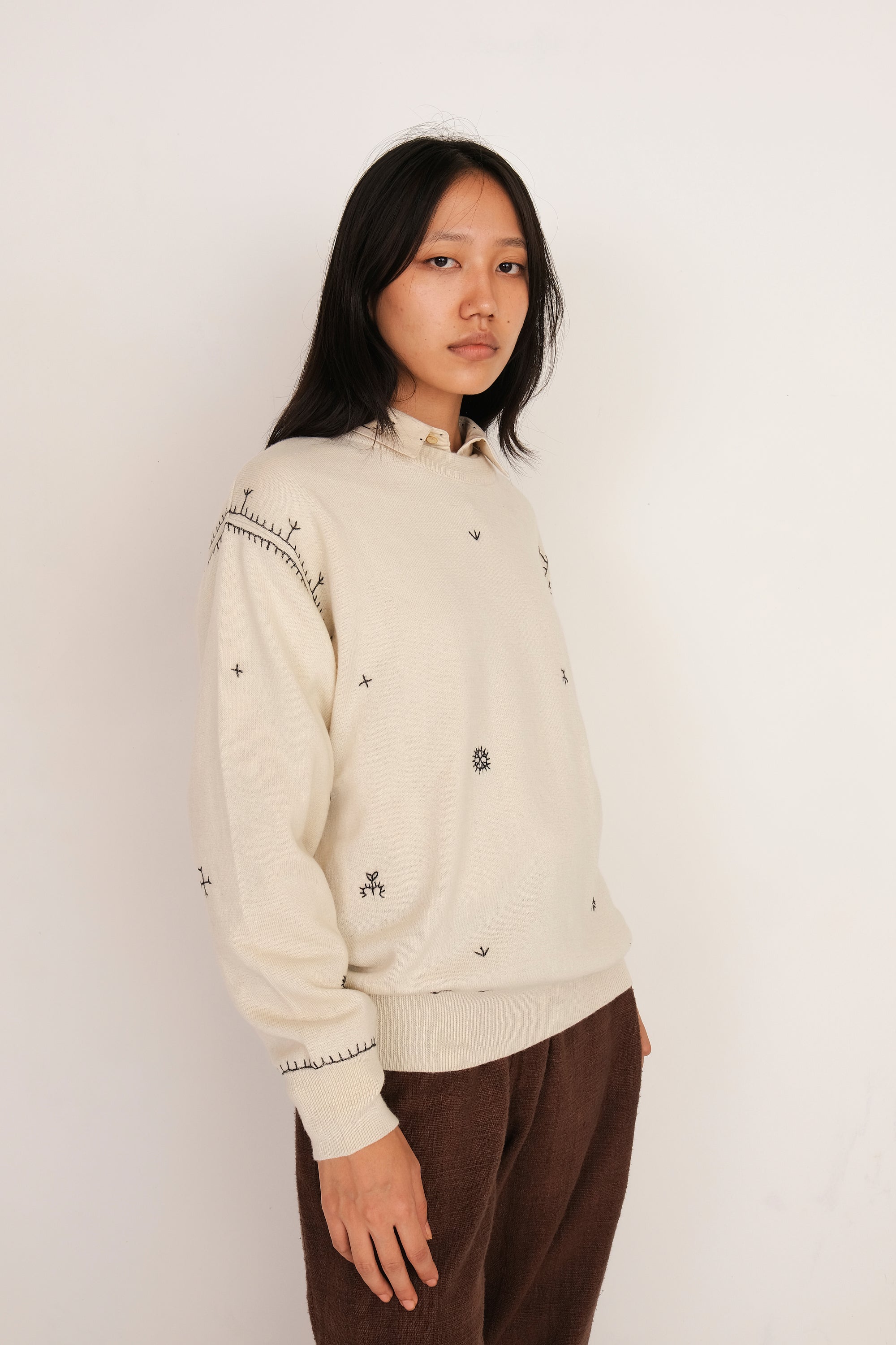 A side shot of a woman wearing ecru sweatshirt shirt
