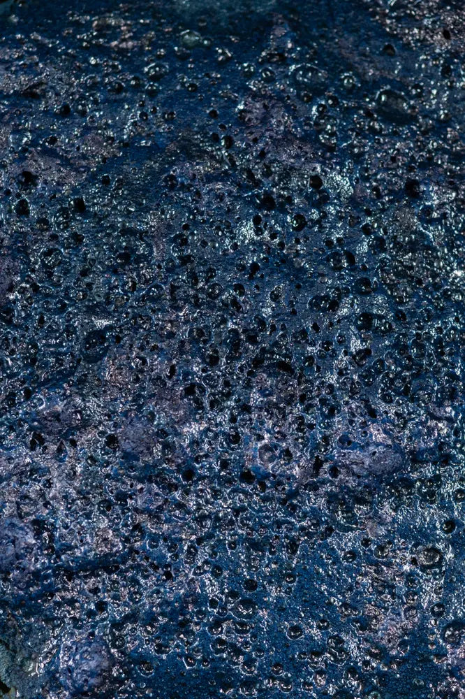 Close-up of a textured indigo surface with black specks
