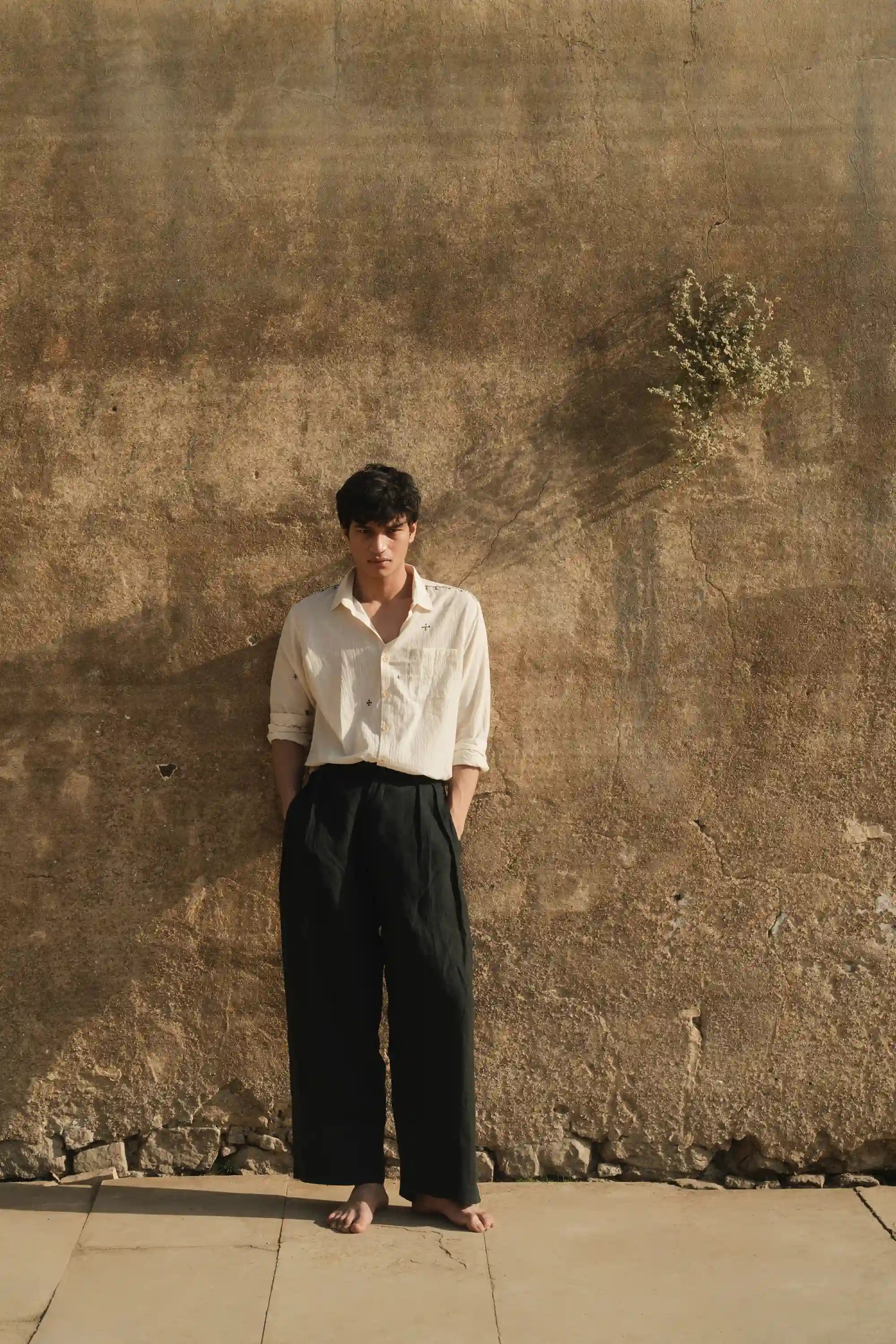 A man wearing a black cotton pant with hand embroidery ecru cotton shirt