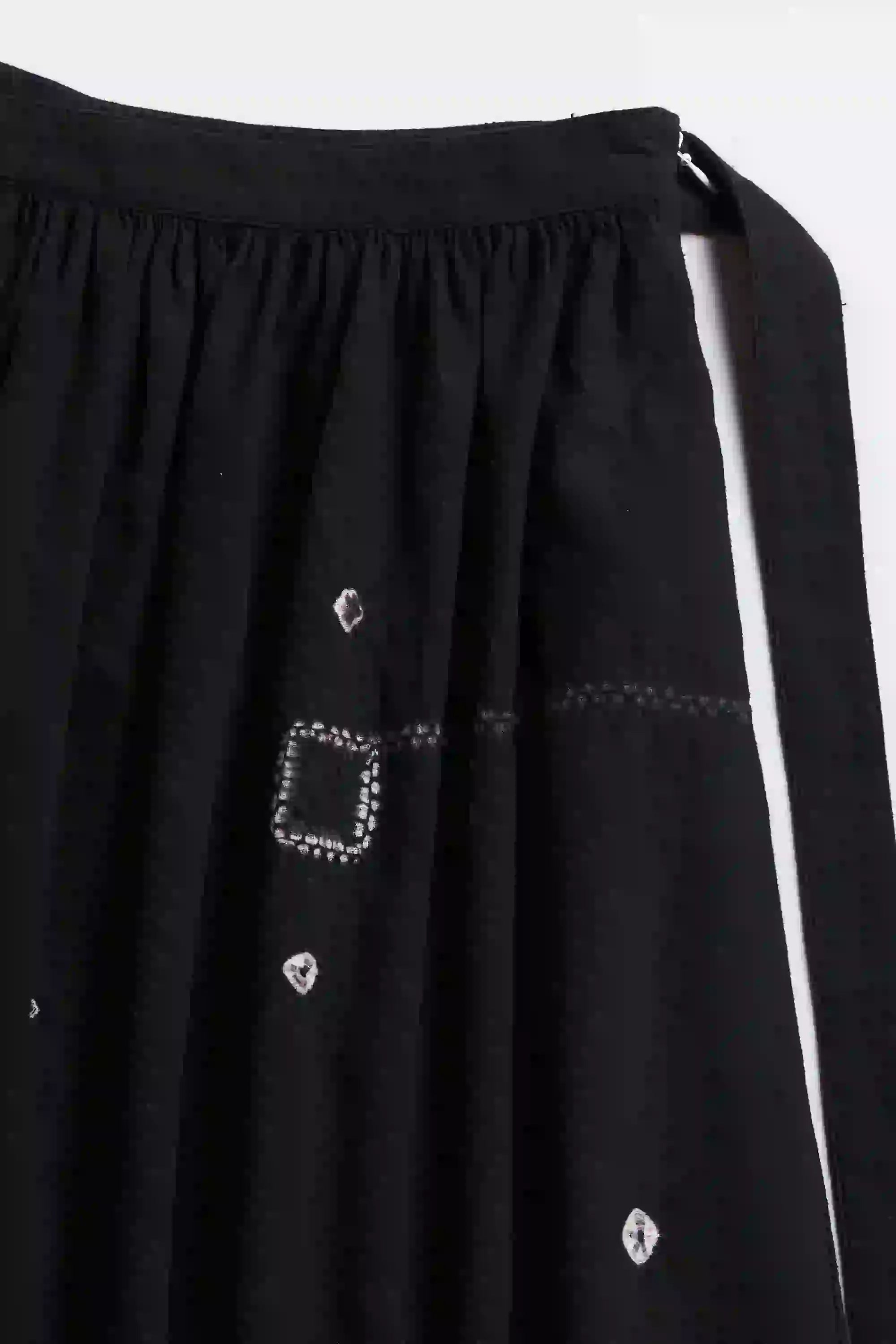 Close-up skirt with white Shibori and embellishments on a greybackground