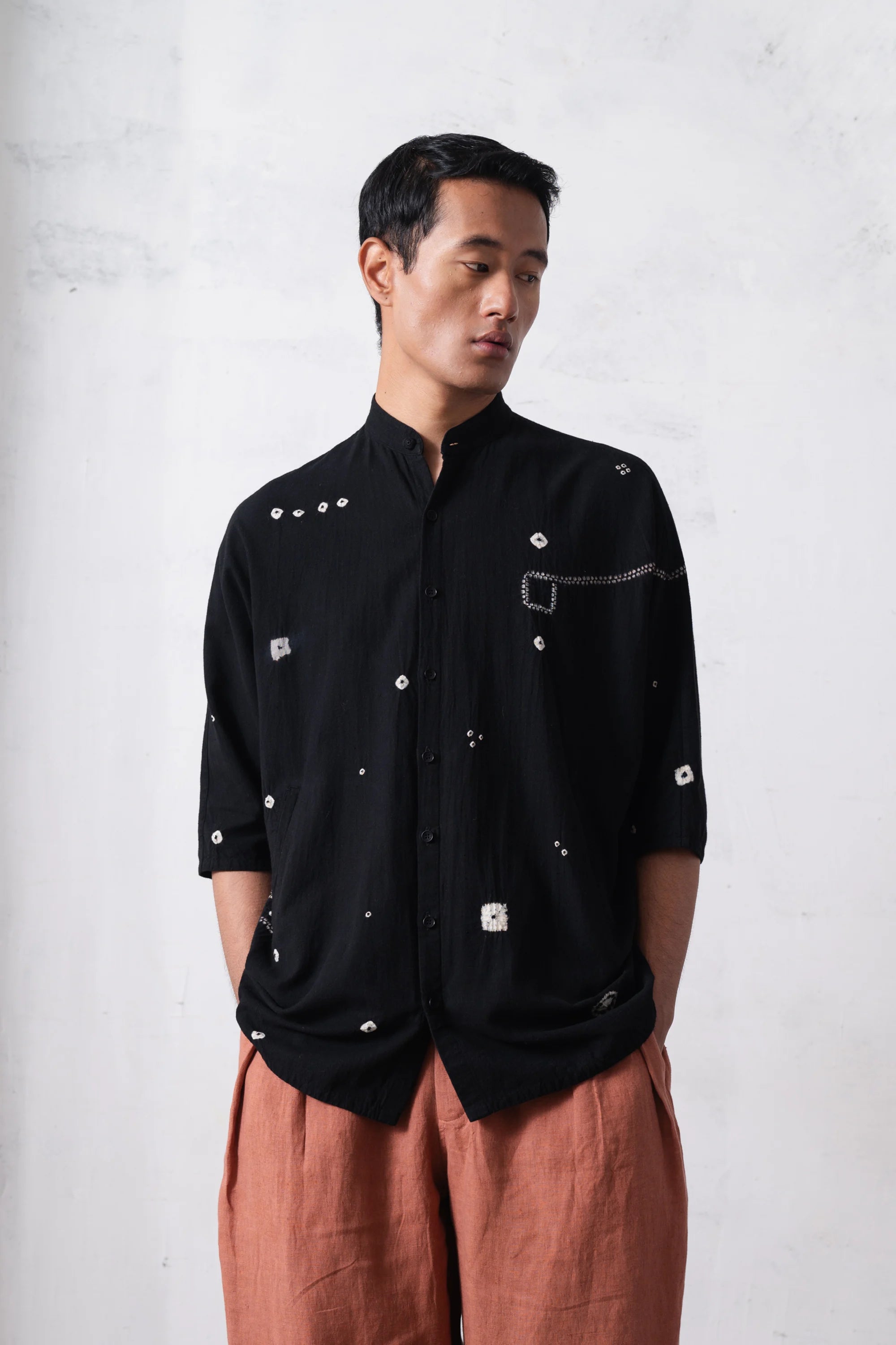 Man wearing a black shirt with shibori work on a light grey background
