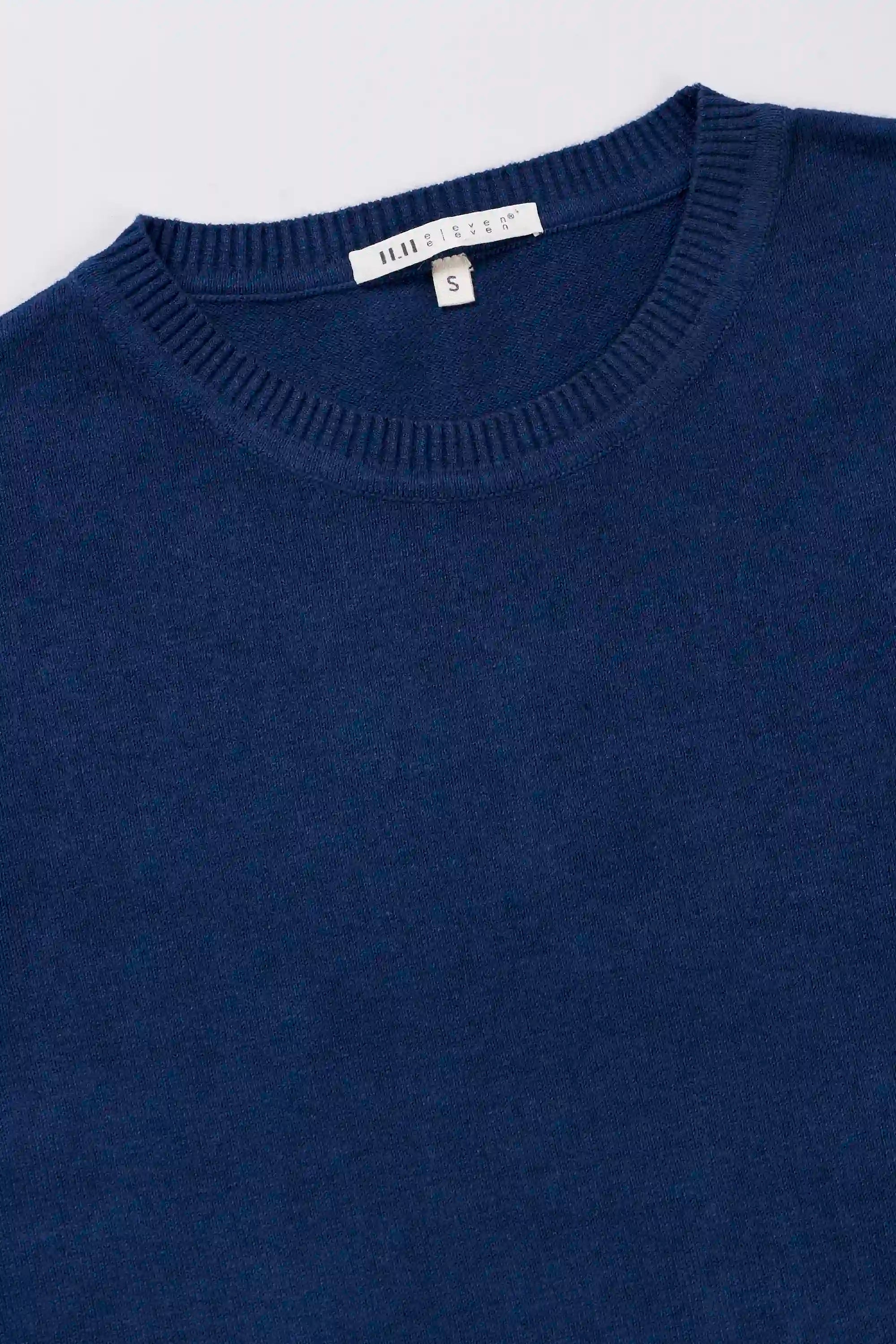 Close-up of a indigo t-shirt with a brand label on a grey background