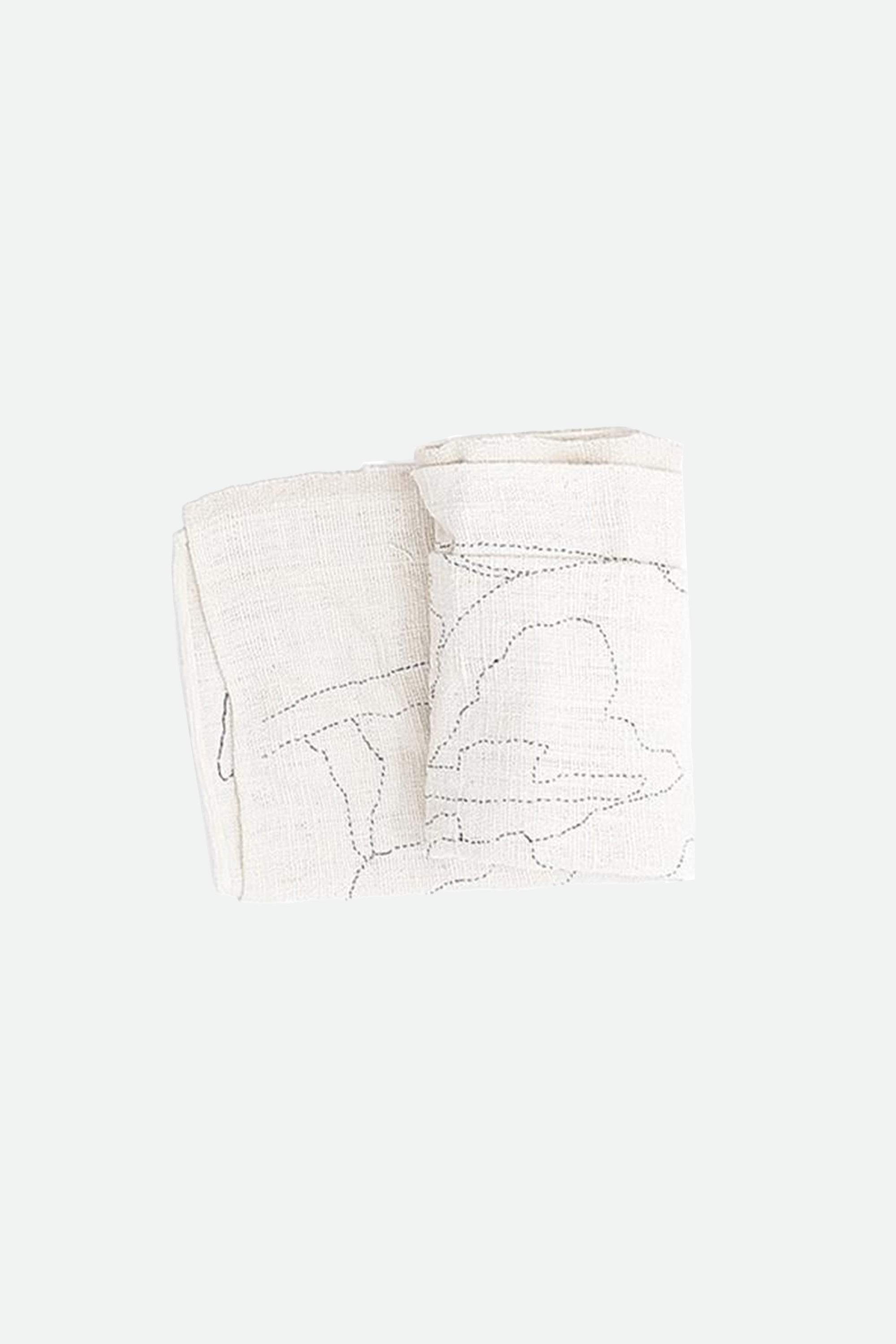 Folded ecru quilt with floral embroidery on a grey background