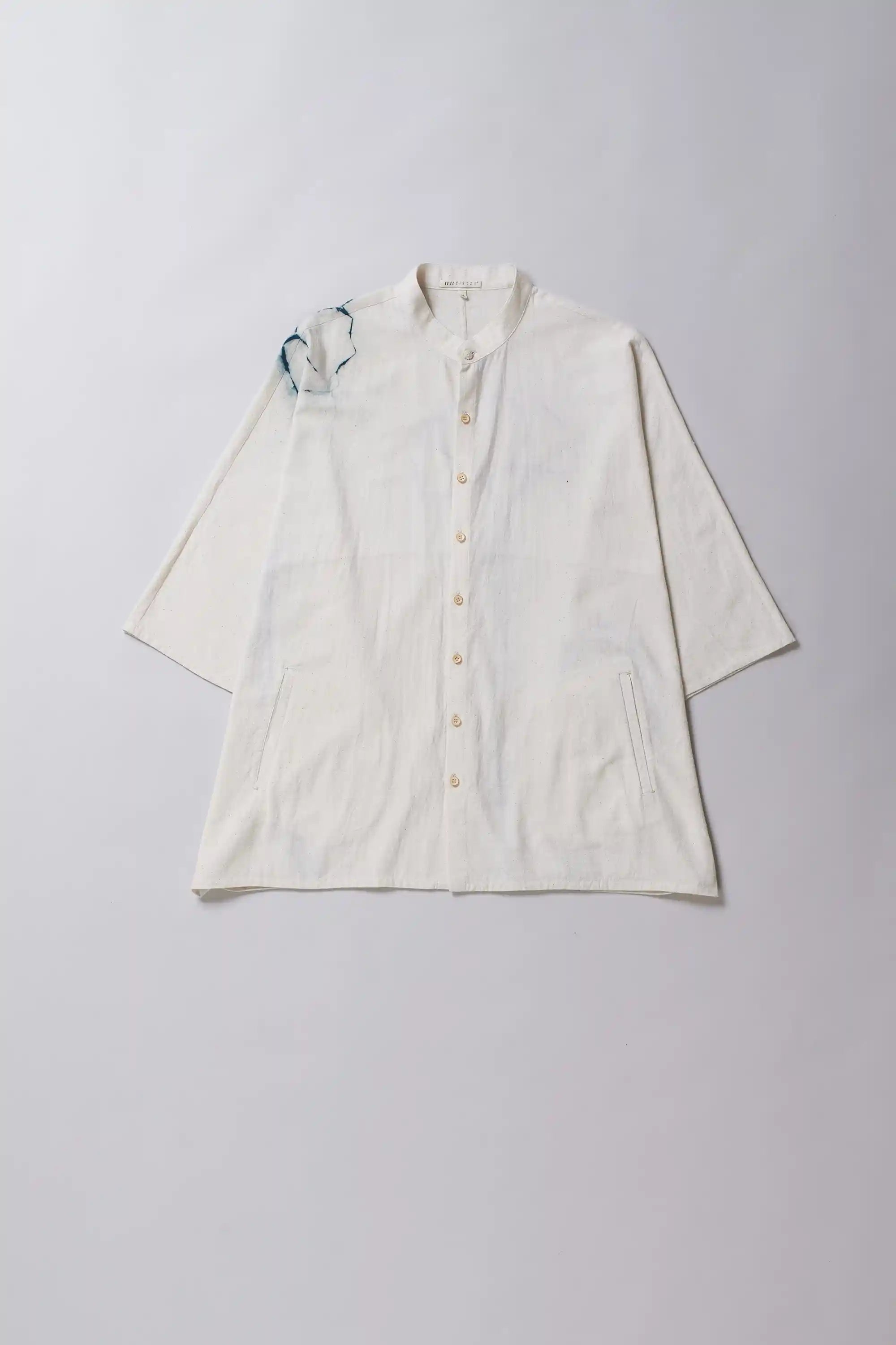 Ecru shirt with shibori artwork on a grey background