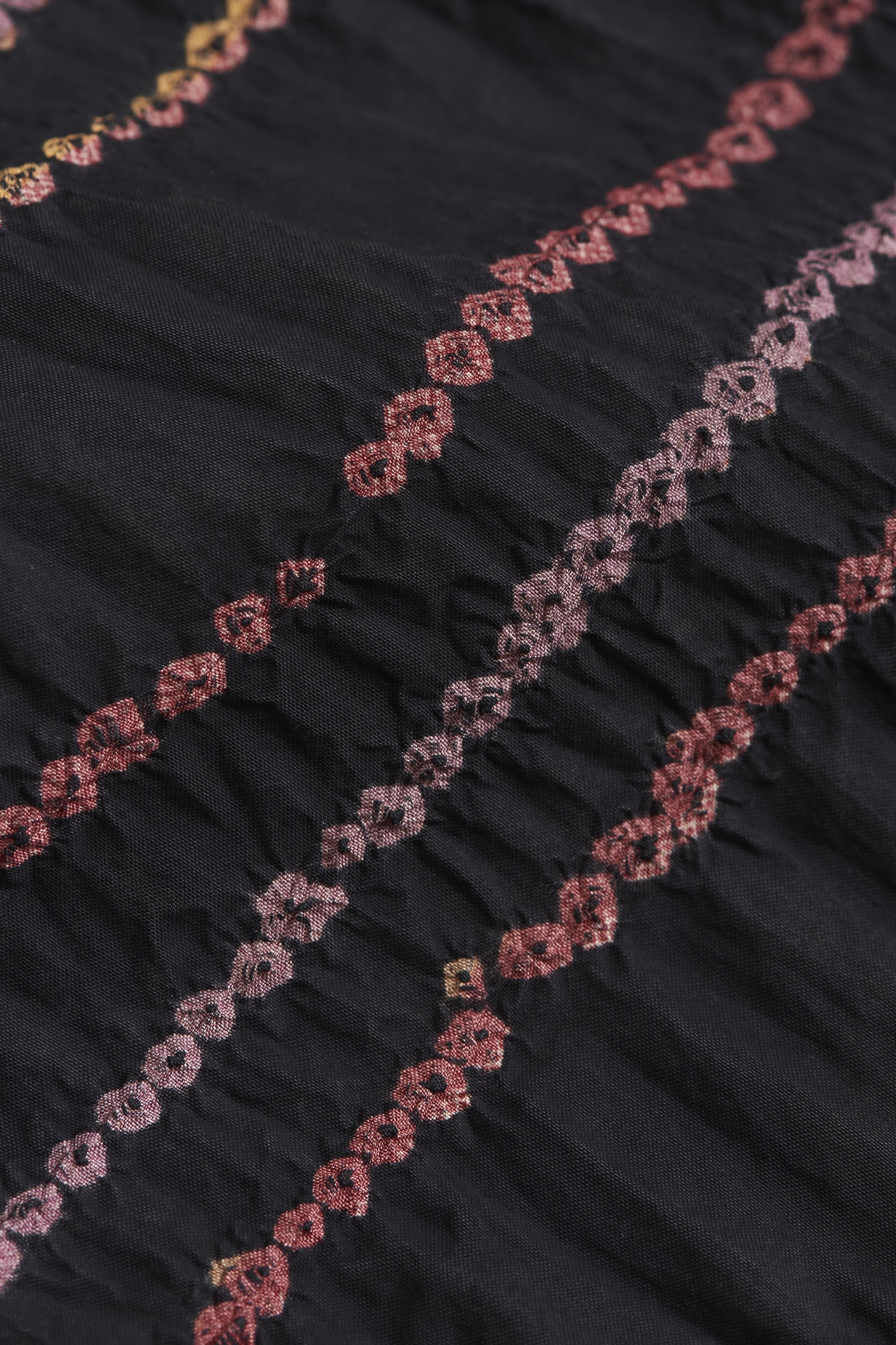 Close-up of black fabric with pink floral embroidery