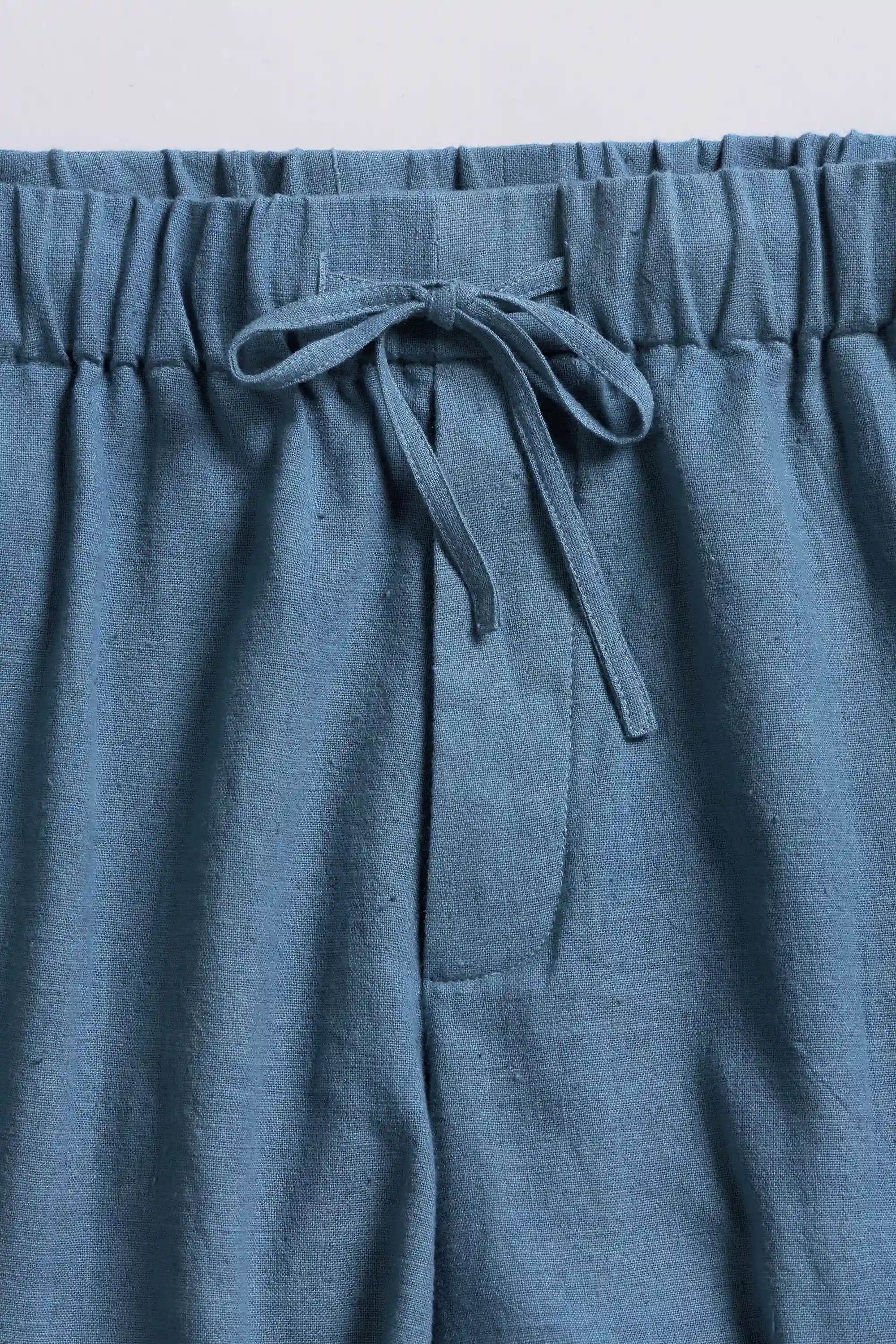 Blue pants with waistband and drawstring on a light grey background