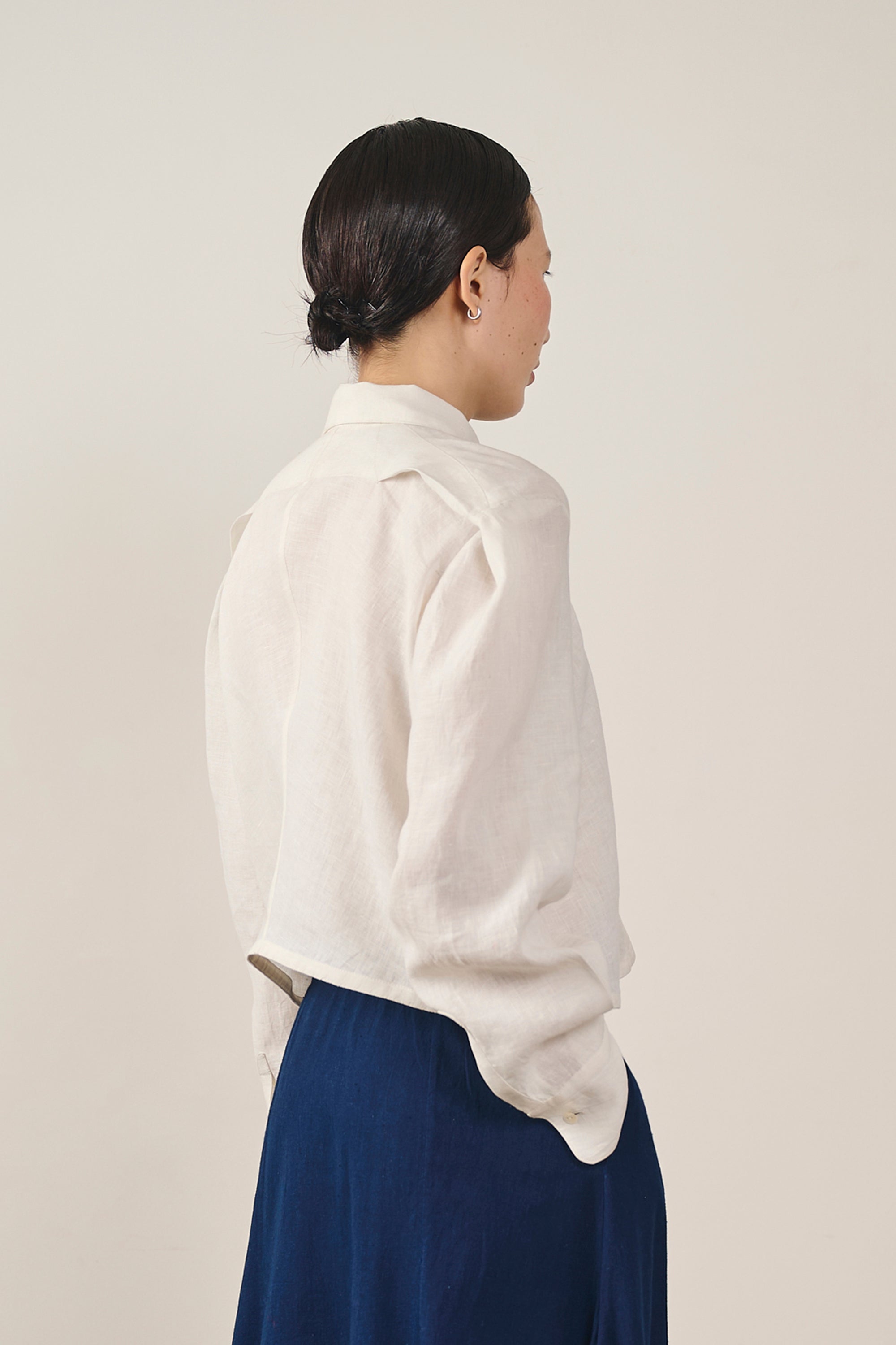 A side shot of a woman wearing ecru shirt