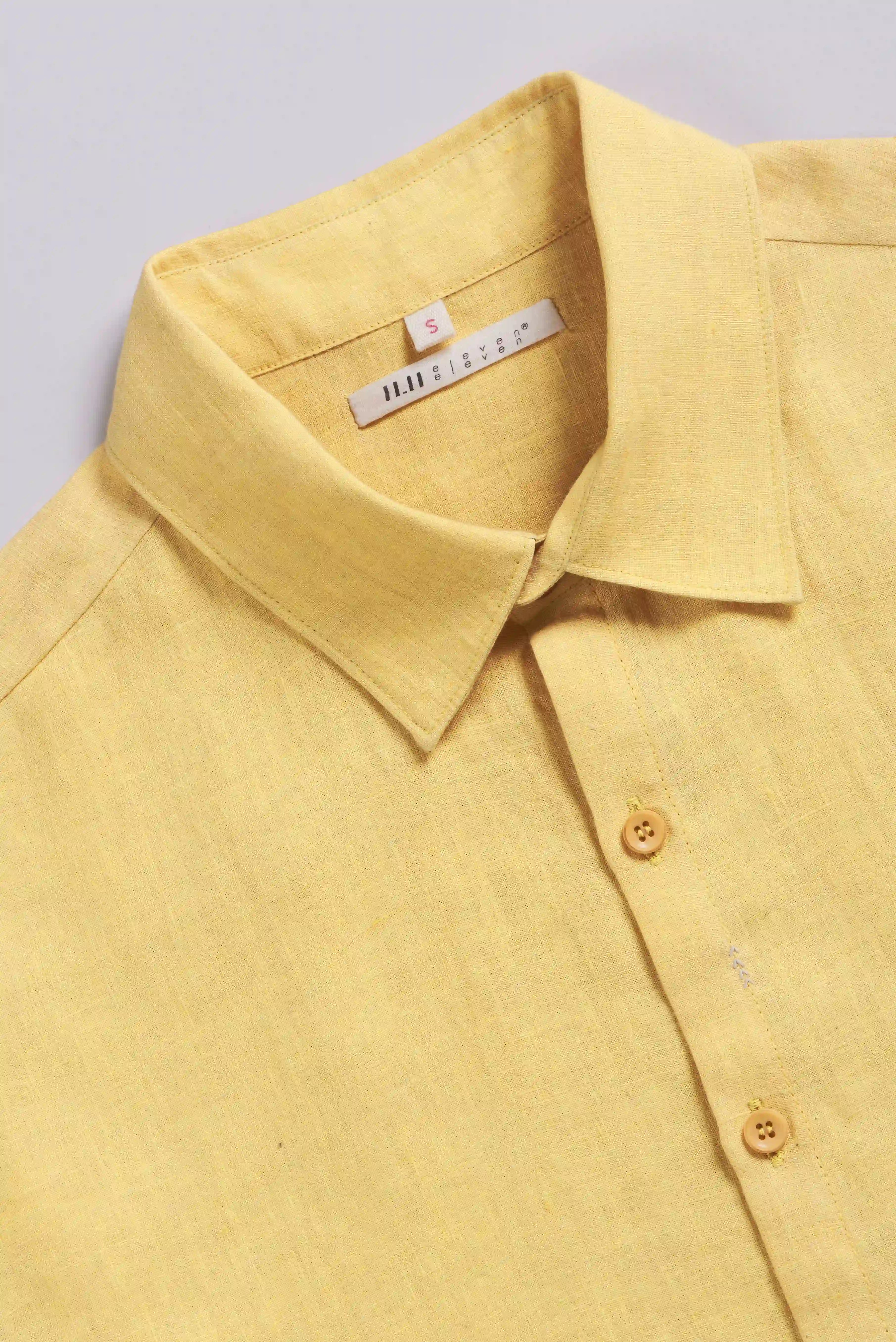 Yellow shirt with a collar and buttons on a light grey background
