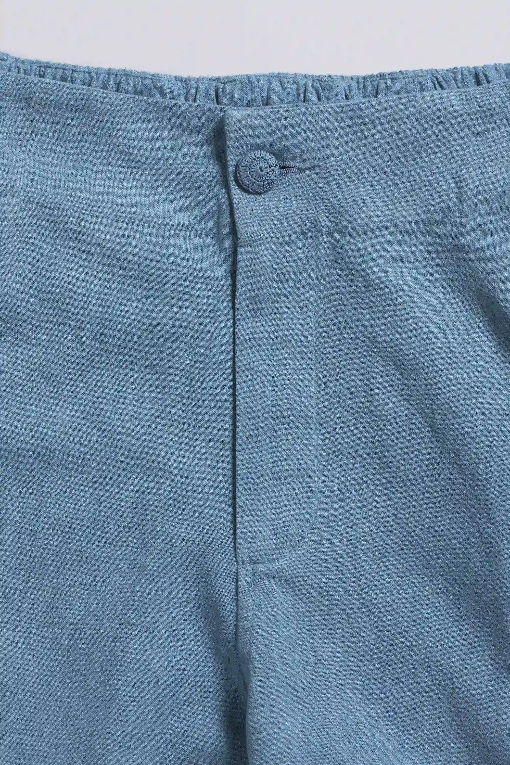 Close-up of blue cotton fabric with a button on a light grey background