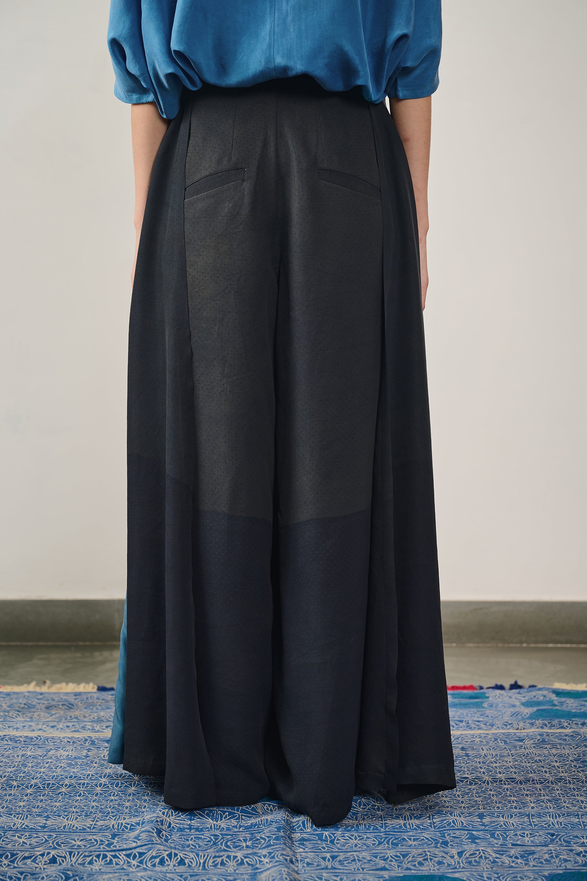 A side shot of a woman wearing black silk trouser