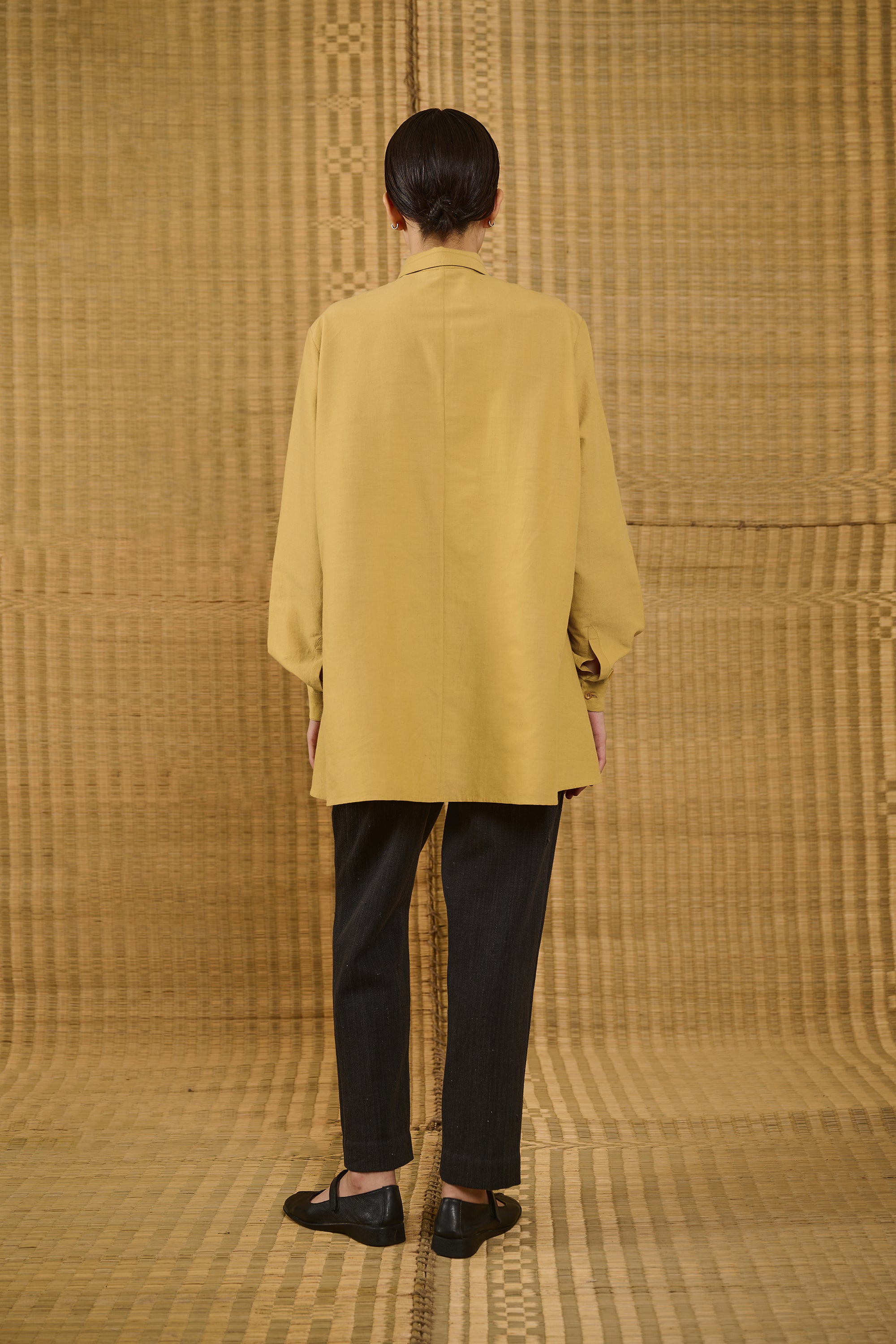 A back shot of a woman wearing mustard yellow shirt