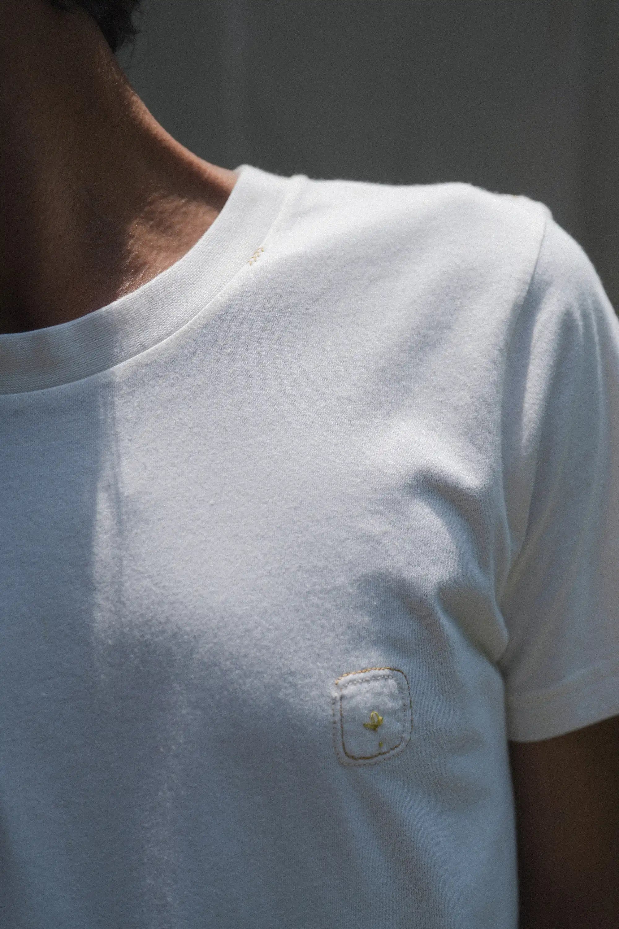 White t-shirt with a small hand detail on a neutral background