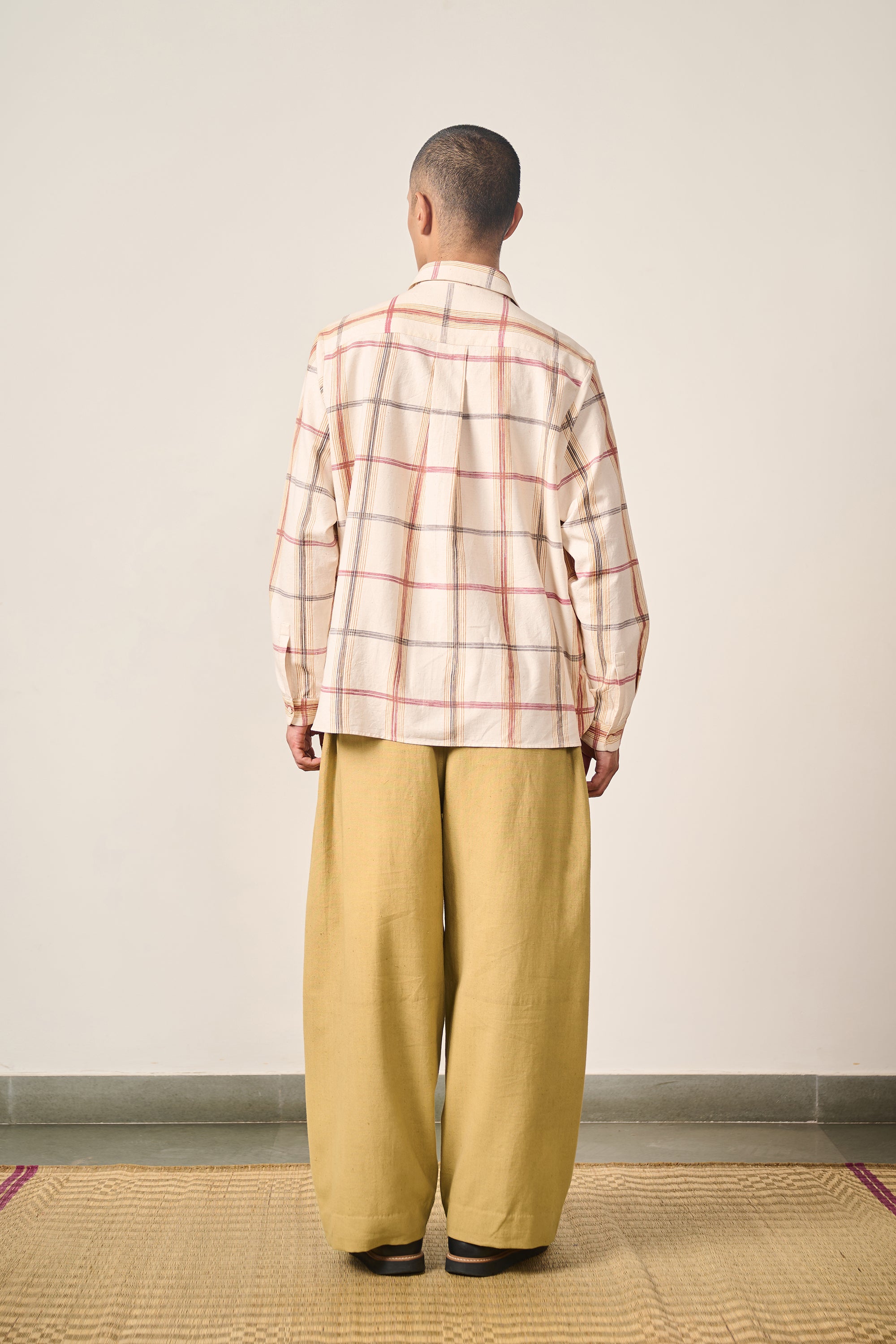 A back shot of a man wearing cream shirt