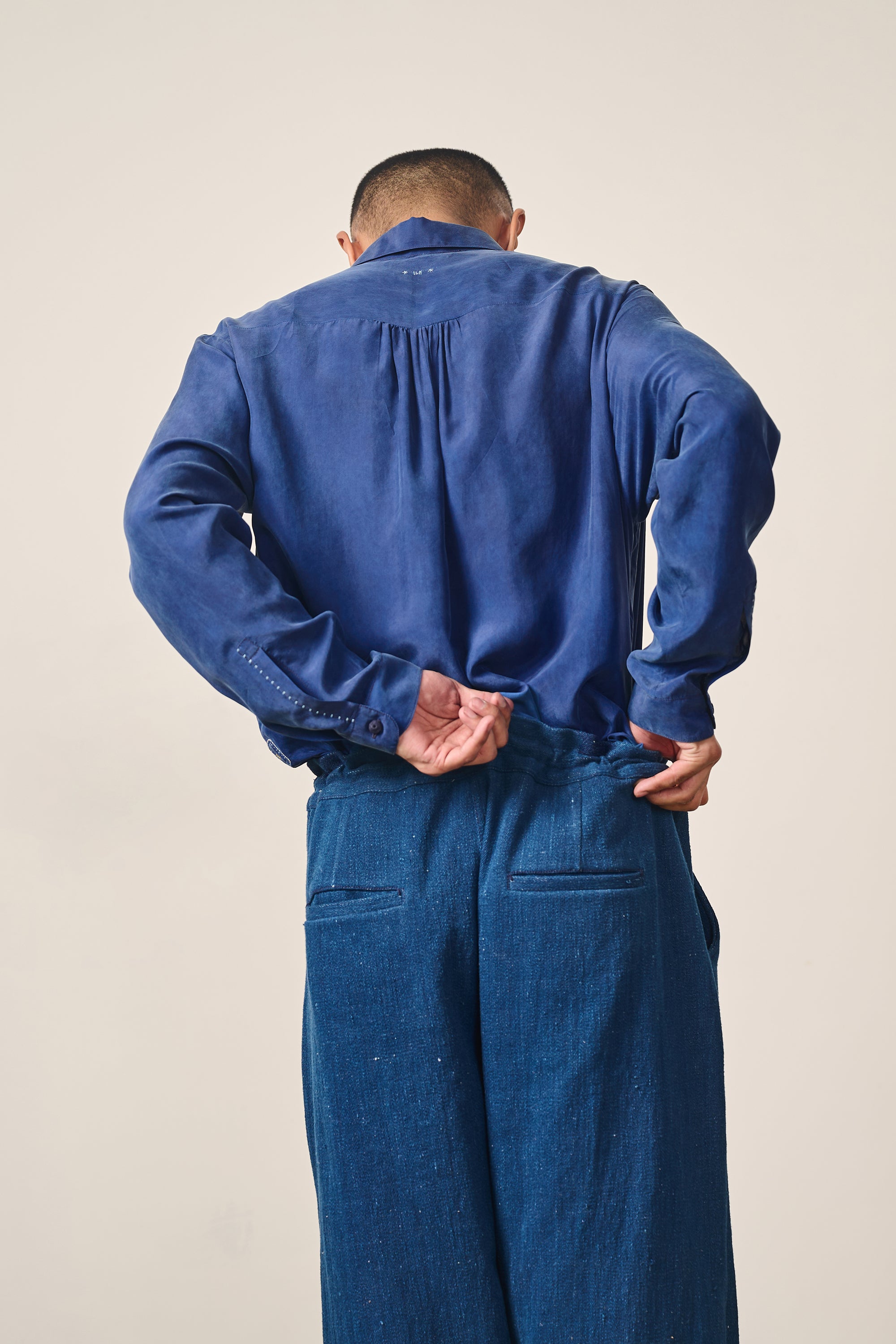 A back shot of a man wearing silk shirt in medium indigo