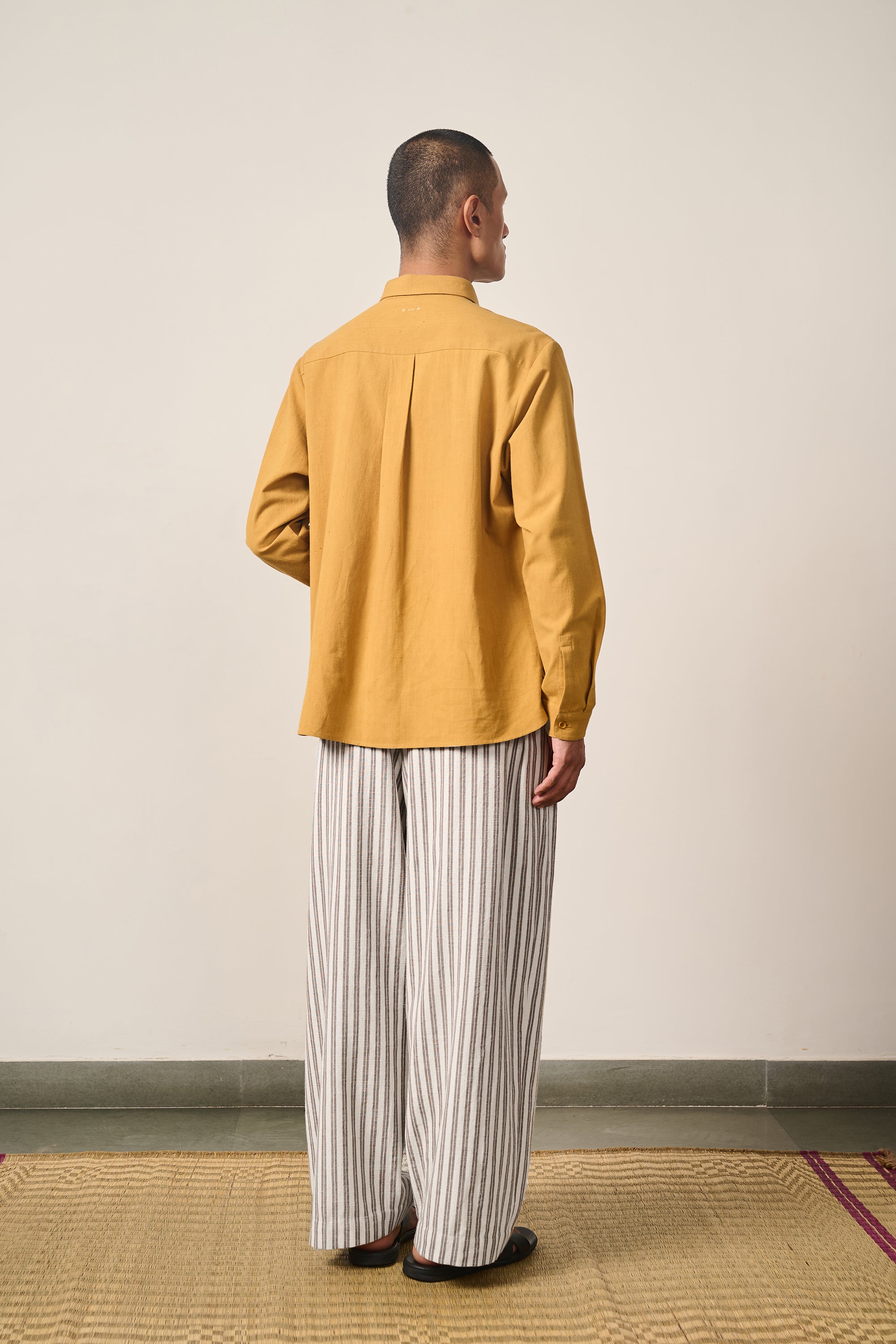 A back shot of a man wearing cotton shirt in mustard yellow