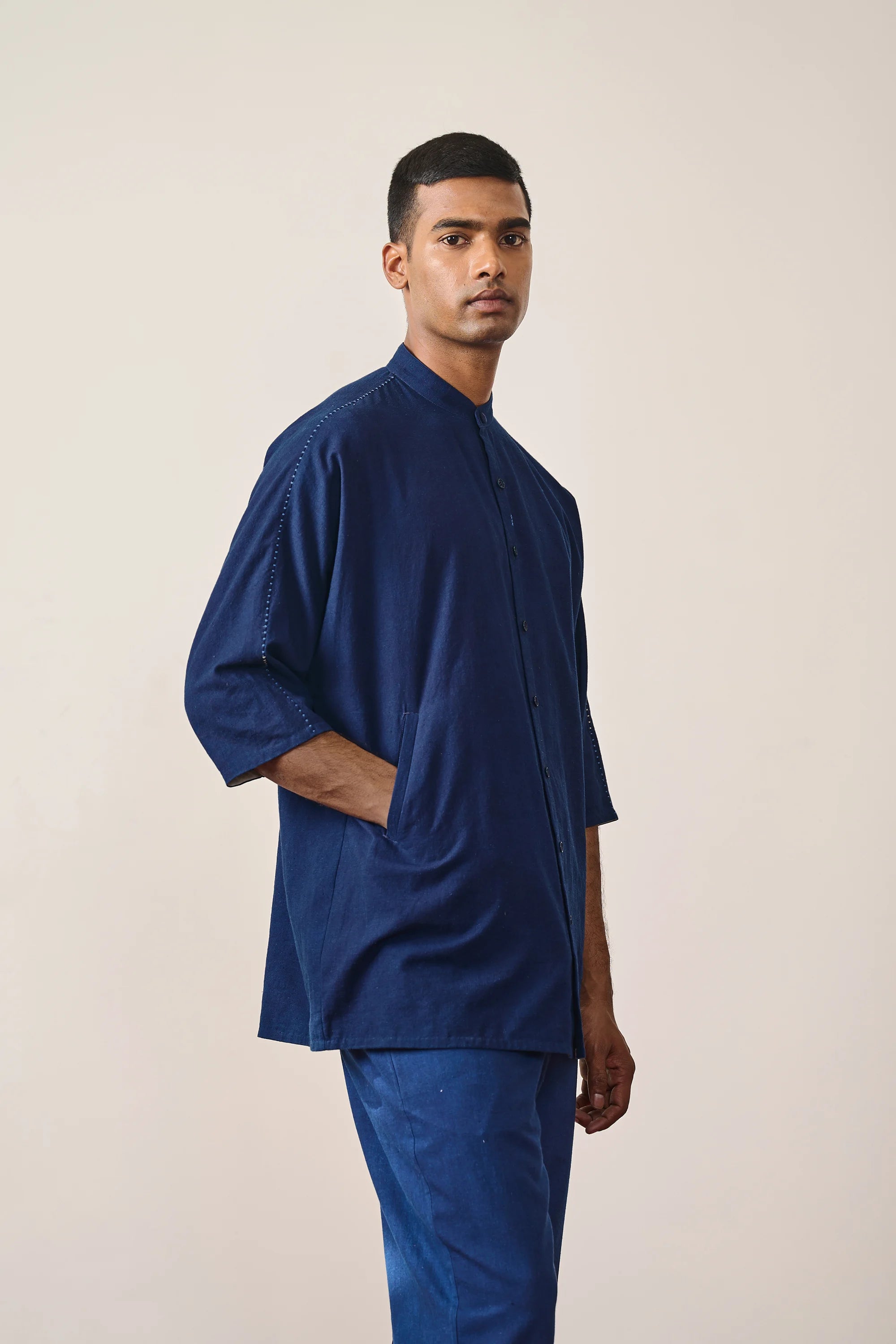 A side shot of a man wearing indigo shirt