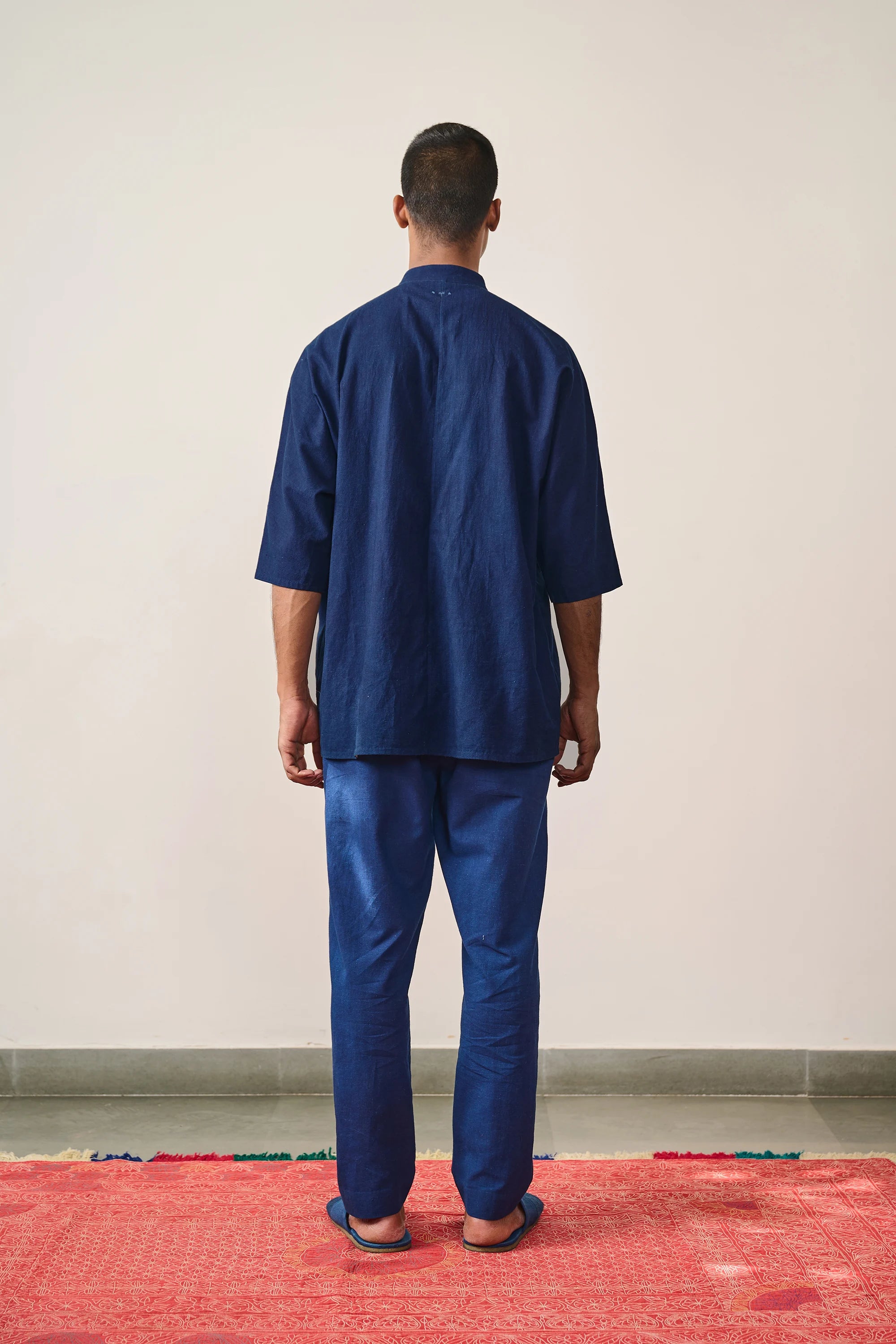 A back shot of a man wearing indigo shirt