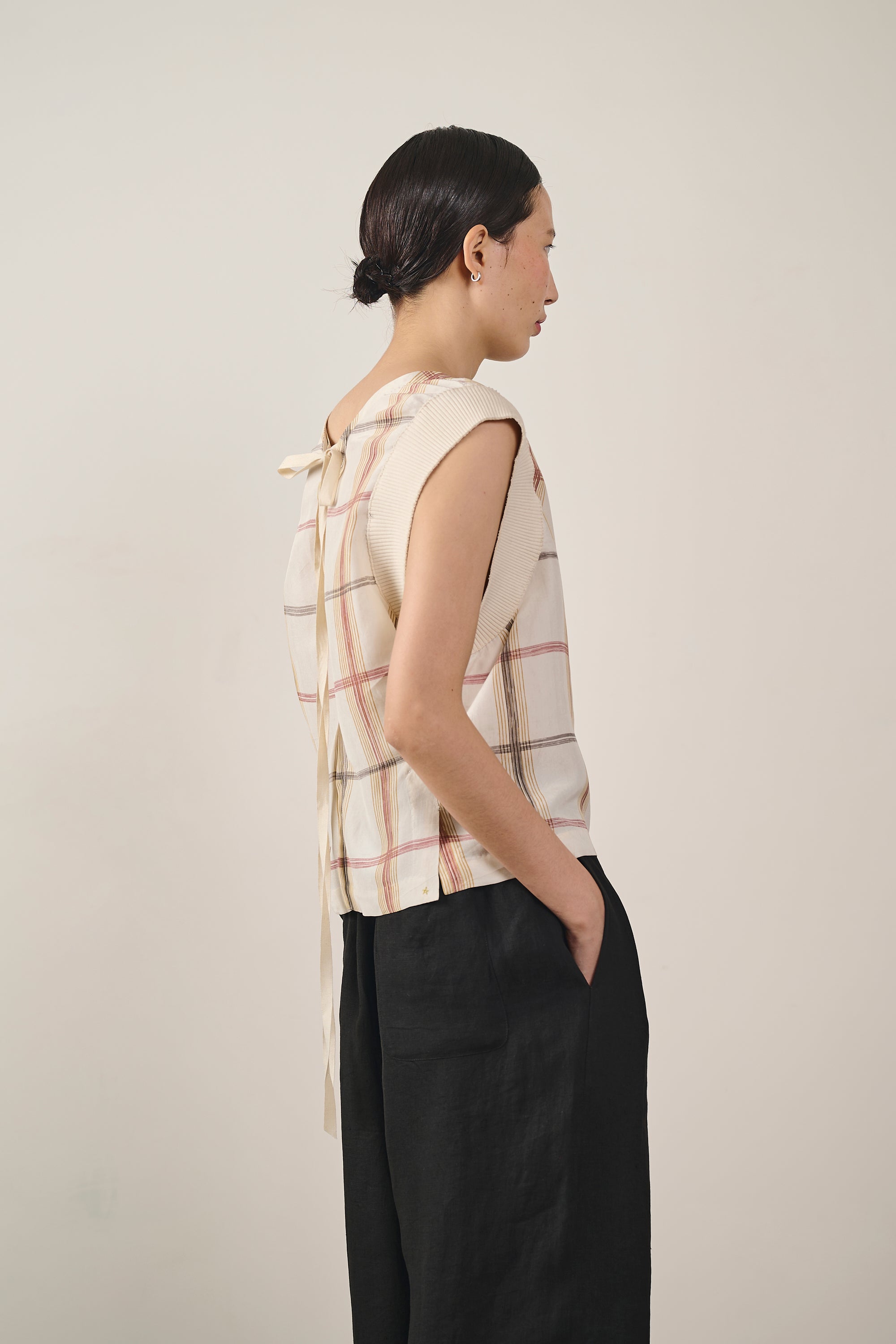 A side shot of a woman wearing silk sleeveless top