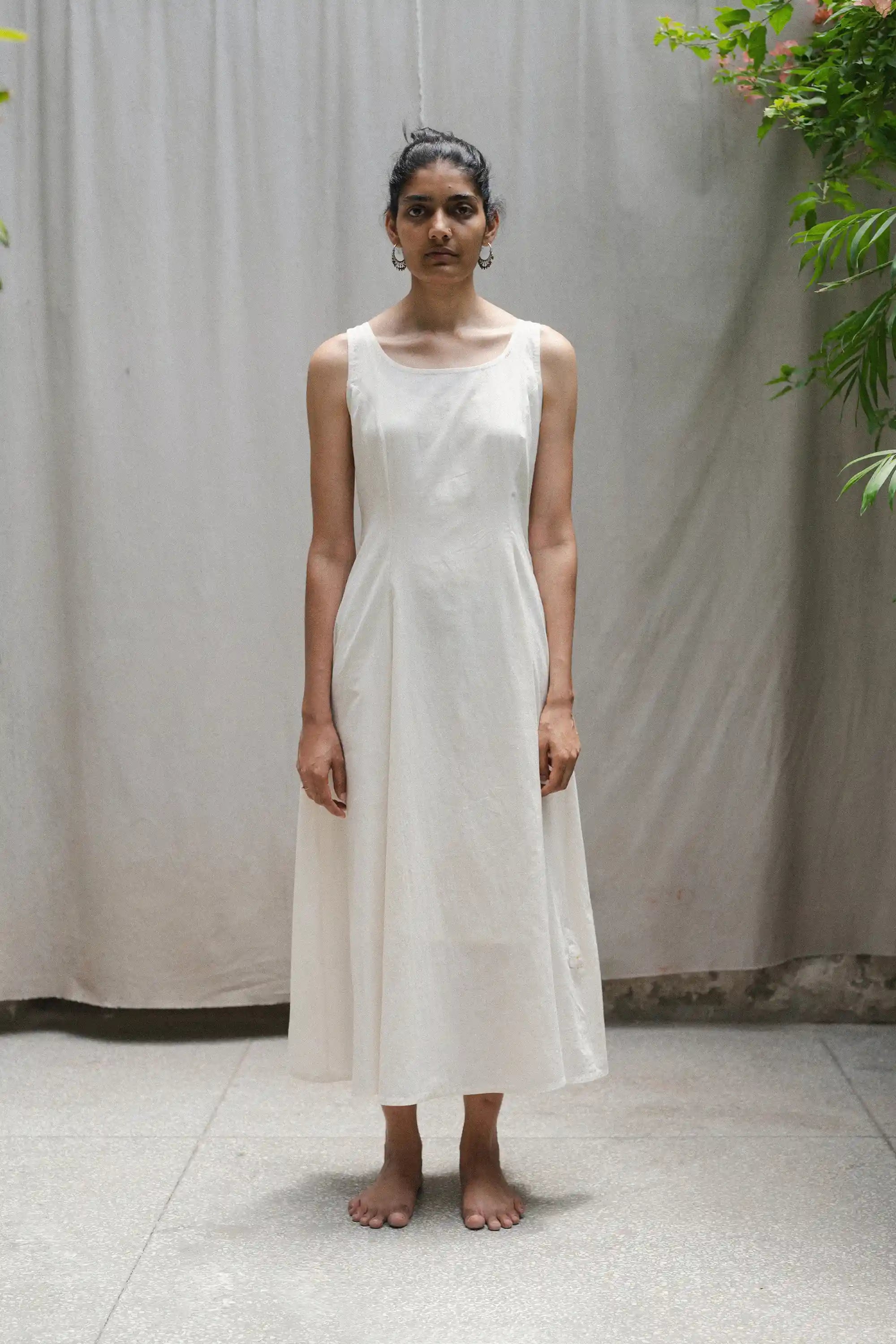 Woman wearing a white dress standing against a plain background