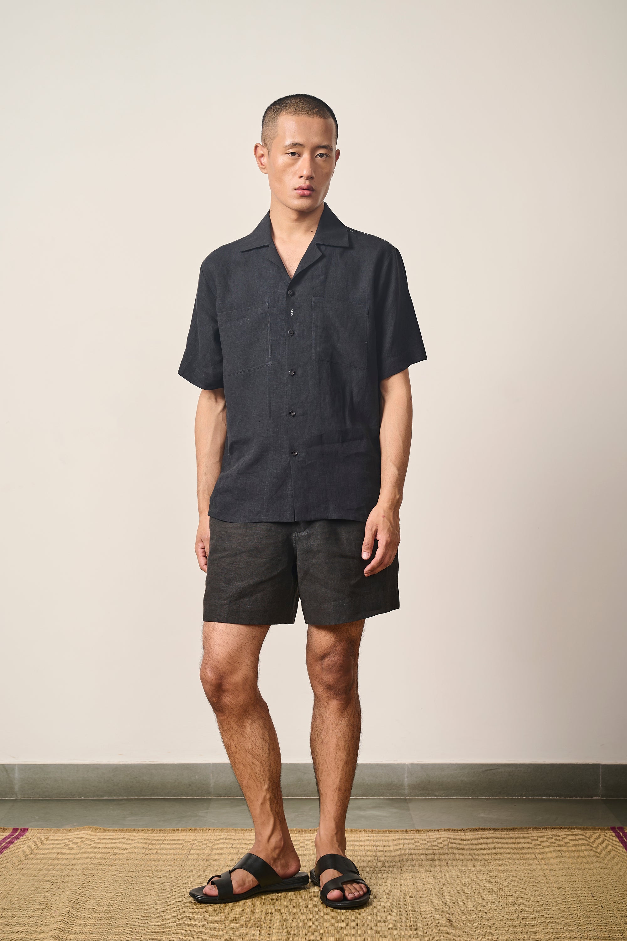 A man wearing black linen shorts