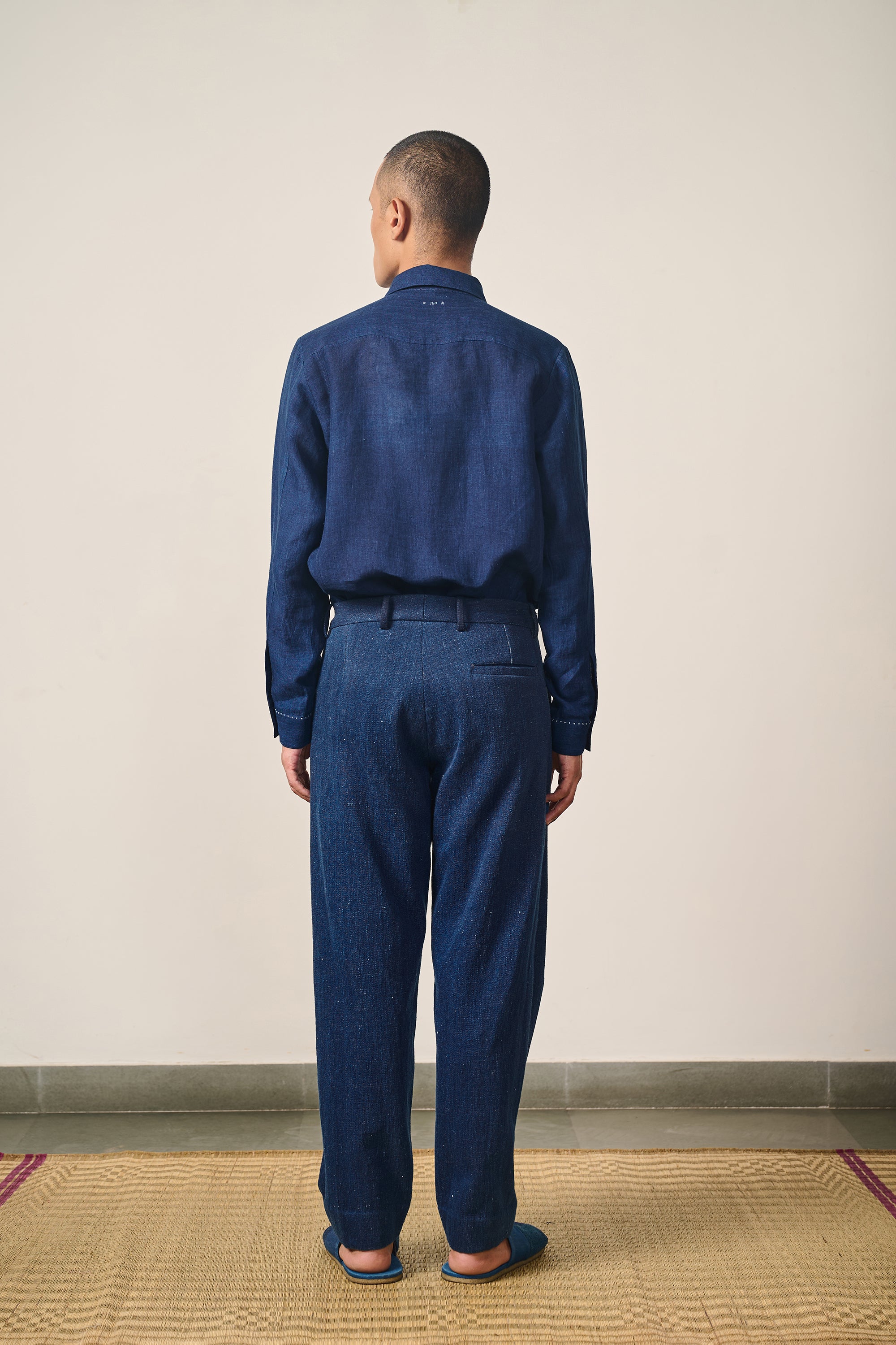 A back shot of a man wearing indigo shirt