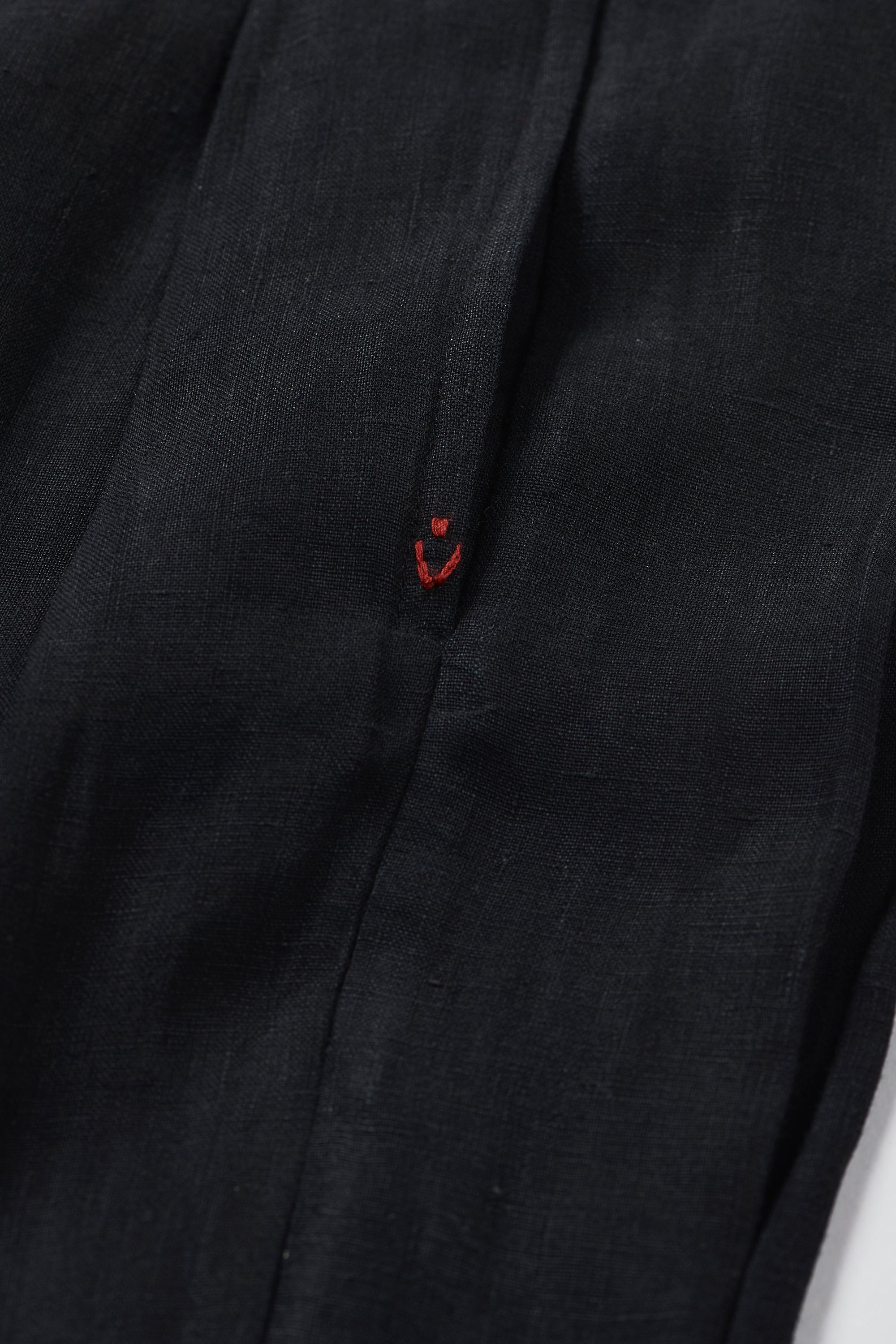 Close-up of a black shirt with a red tread hand detail on a grey background