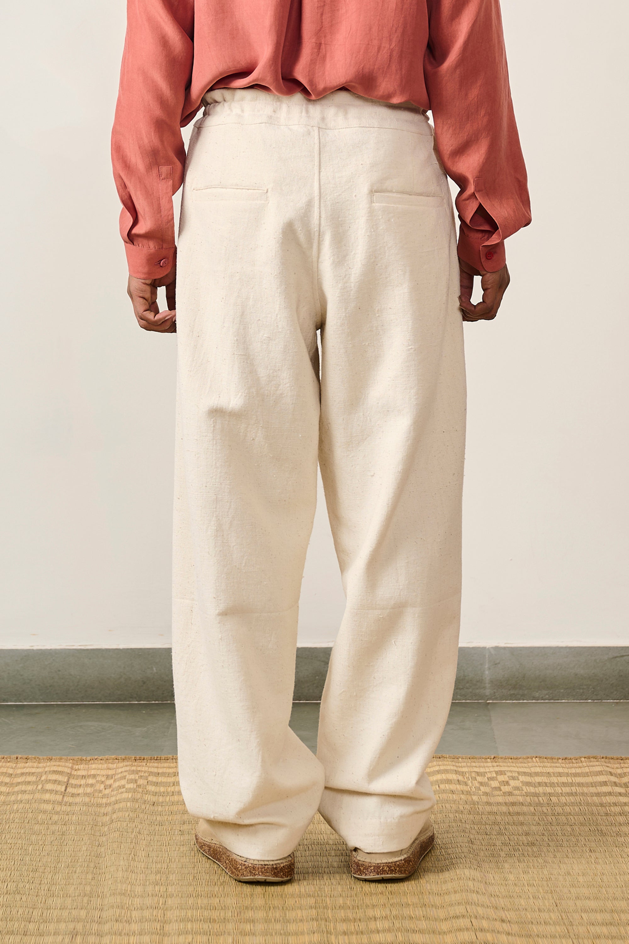 A back shot of a man wearing ecru cotton pant