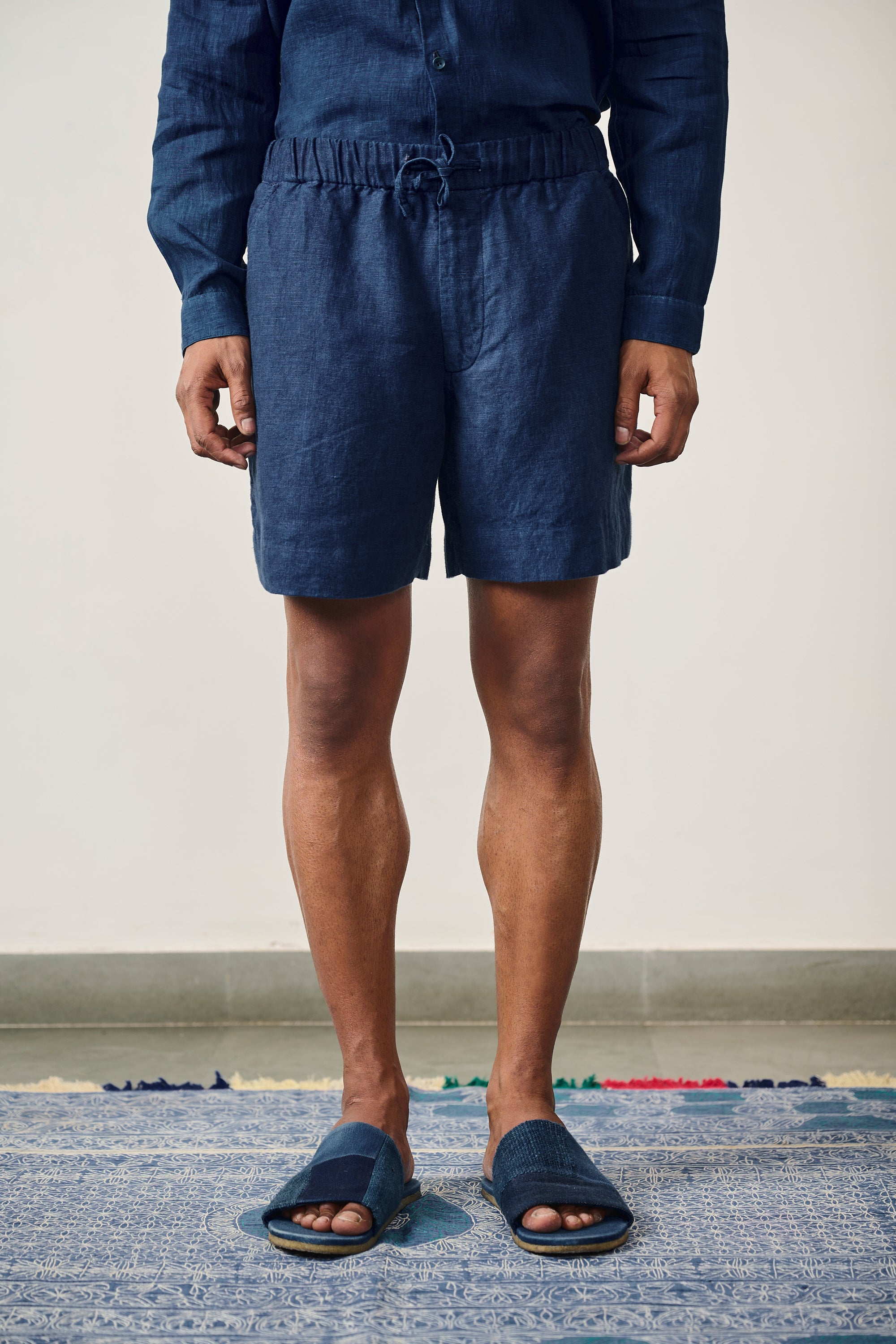 A man wearing medium indigo linen shorts