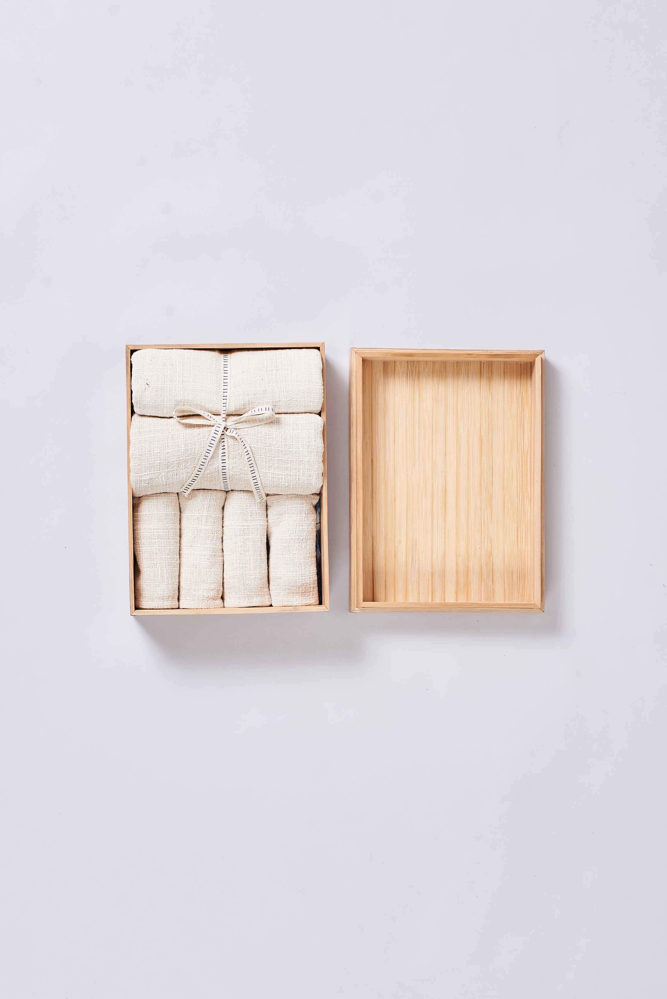 Set of folded towels in a wooden box on a grey background